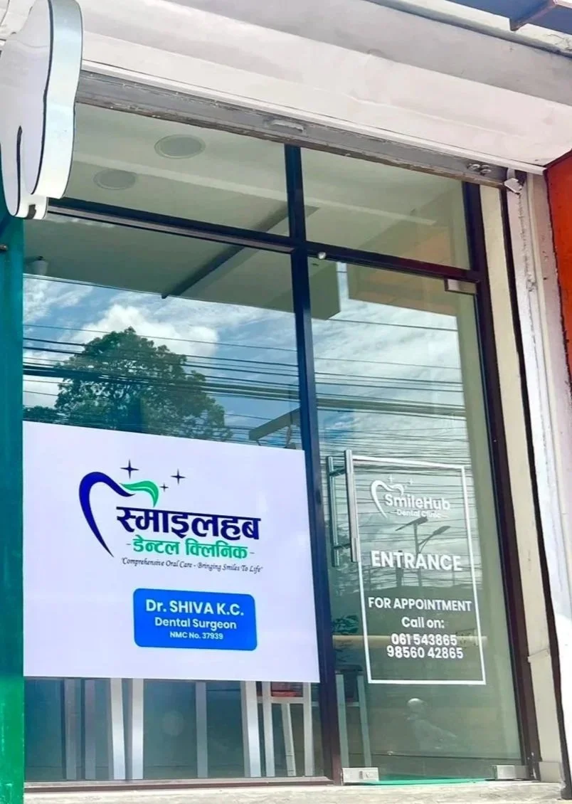 Dental clinic entrance with signs displaying the clinic's name in Nepali, Dr. Shiva K.C., a dental surgeon, and phone numbers for appointments. The clinic also has a sign for SmileHub Dental Care.