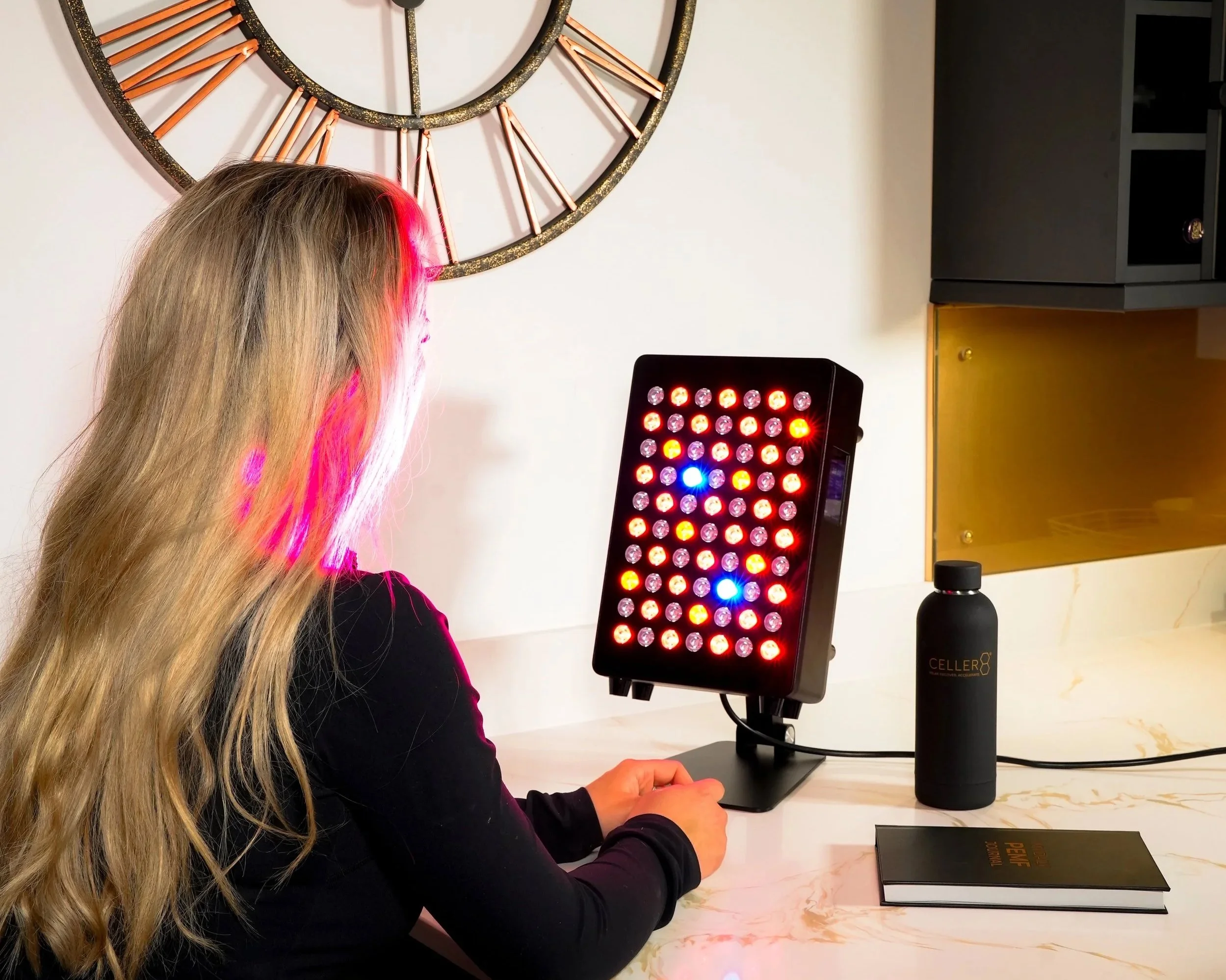 Woman using a clinic-grade red light therapy panel at home, demonstrating full-spectrum red and near-infrared light treatment.