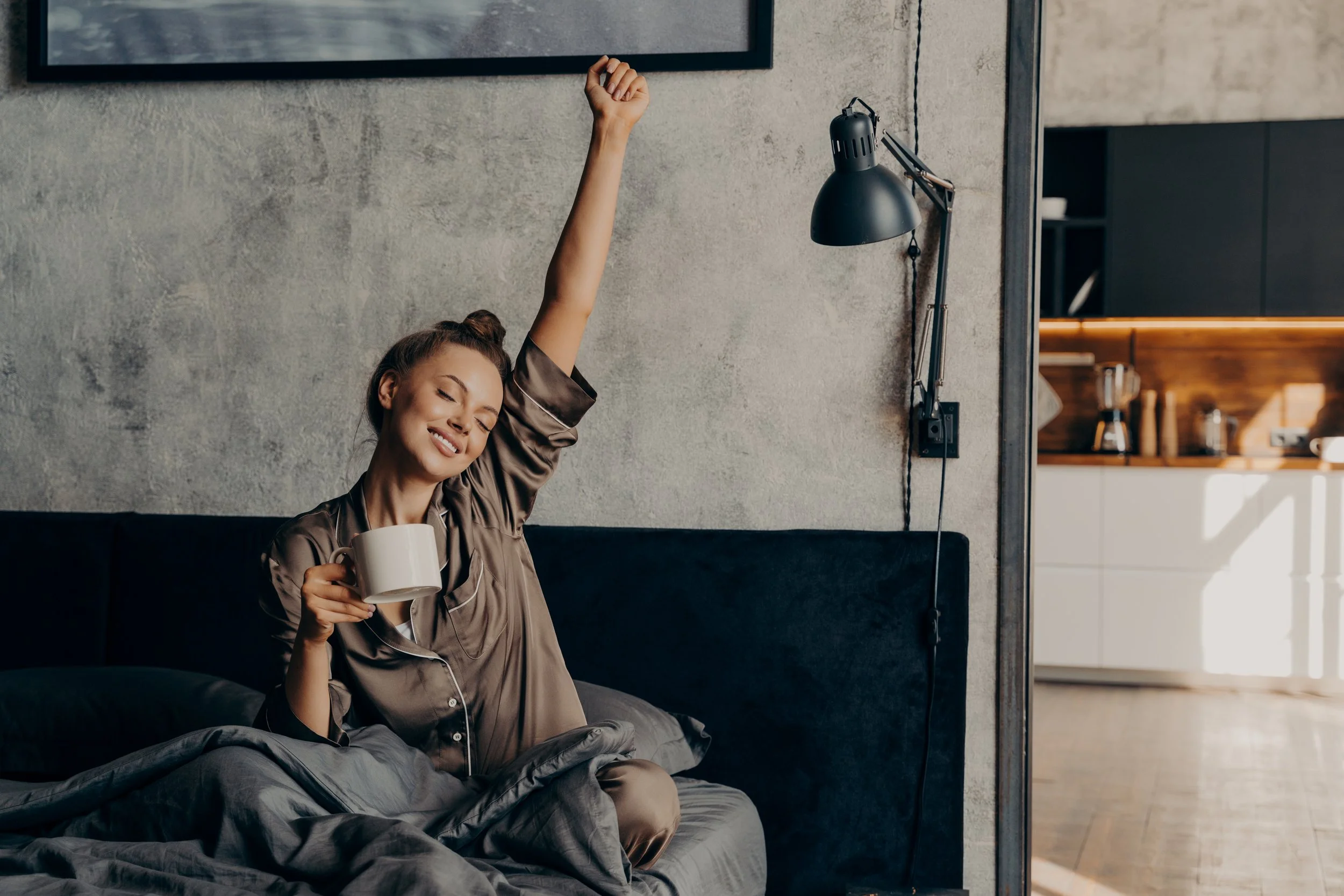 Woman waking up refreshed in bed as part of a healthy morning wellness routine.