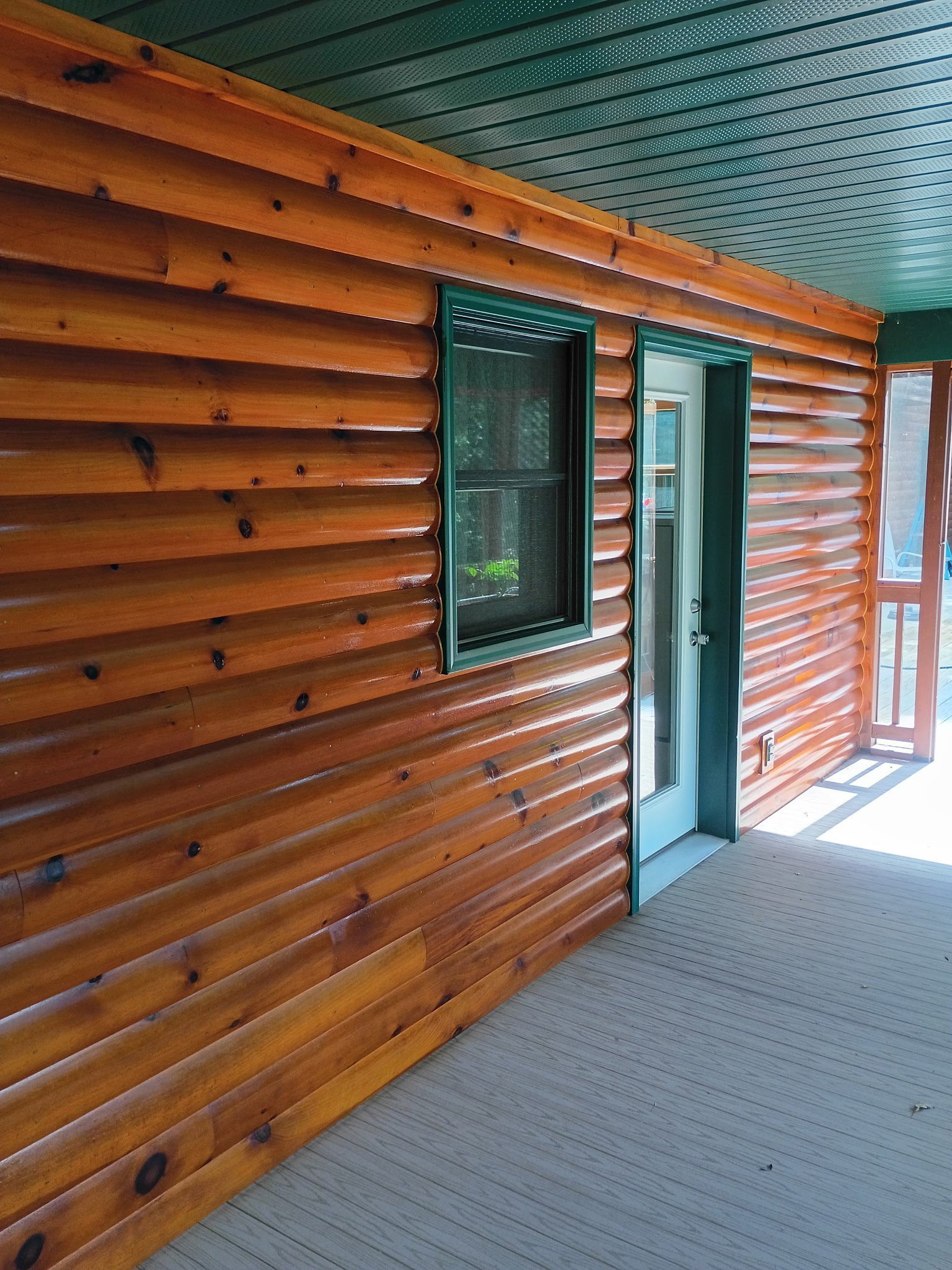 Wooden porch with green-framed window and door, and a screened section on the right.