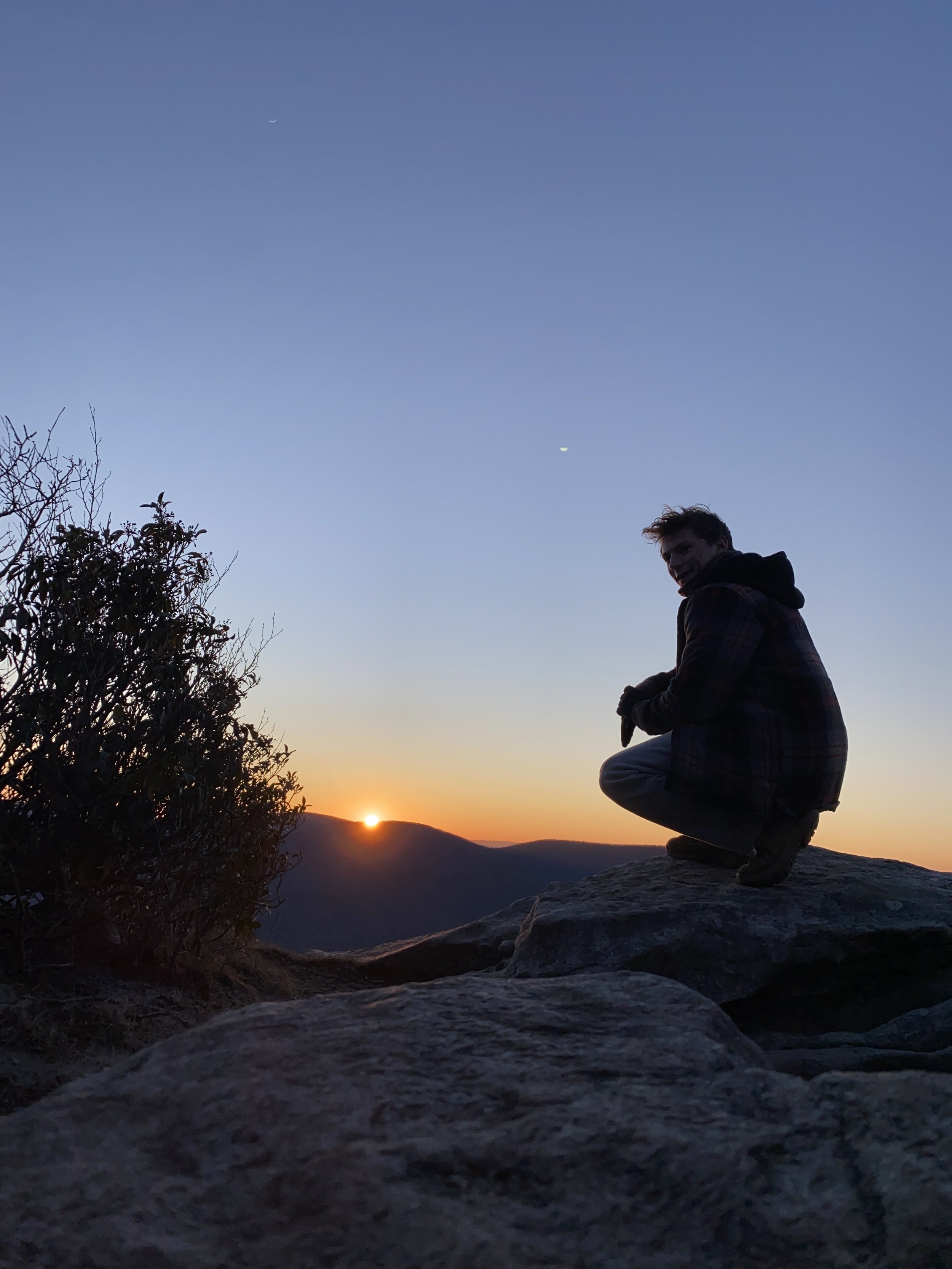 Harrison standing on the edge of a cliff during a beautiful sunset.