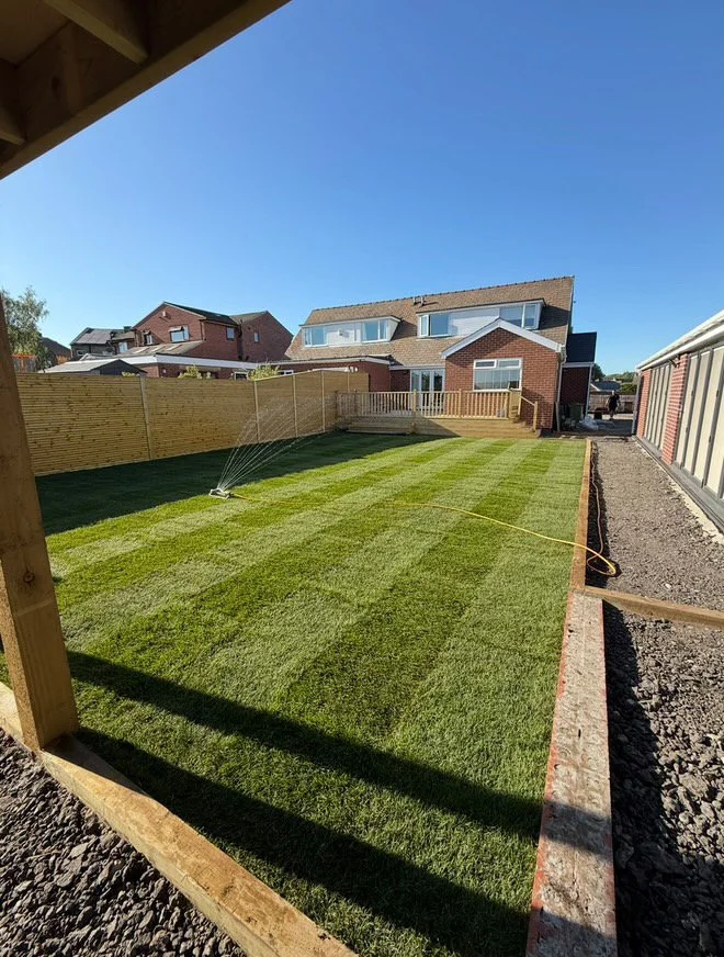 Freshly laid natural turf lawn being watered in a rear garden