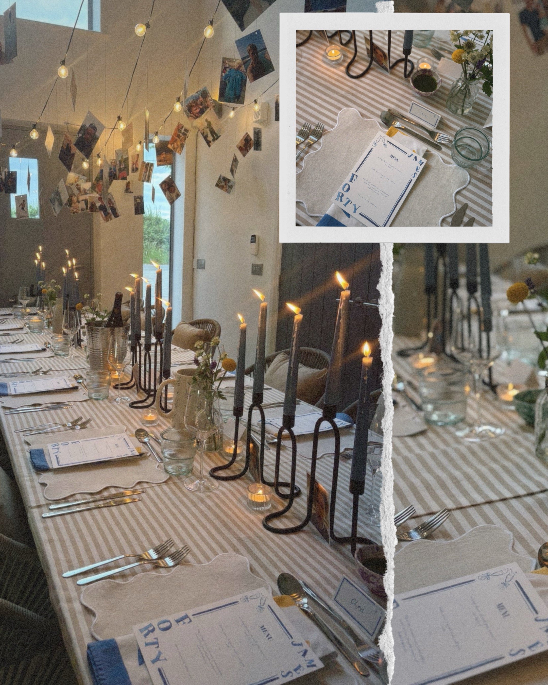A decorated dining table set for a meal with candles, flowers, and place cards, with a string of photographs hanging from the ceiling in a room with windows.