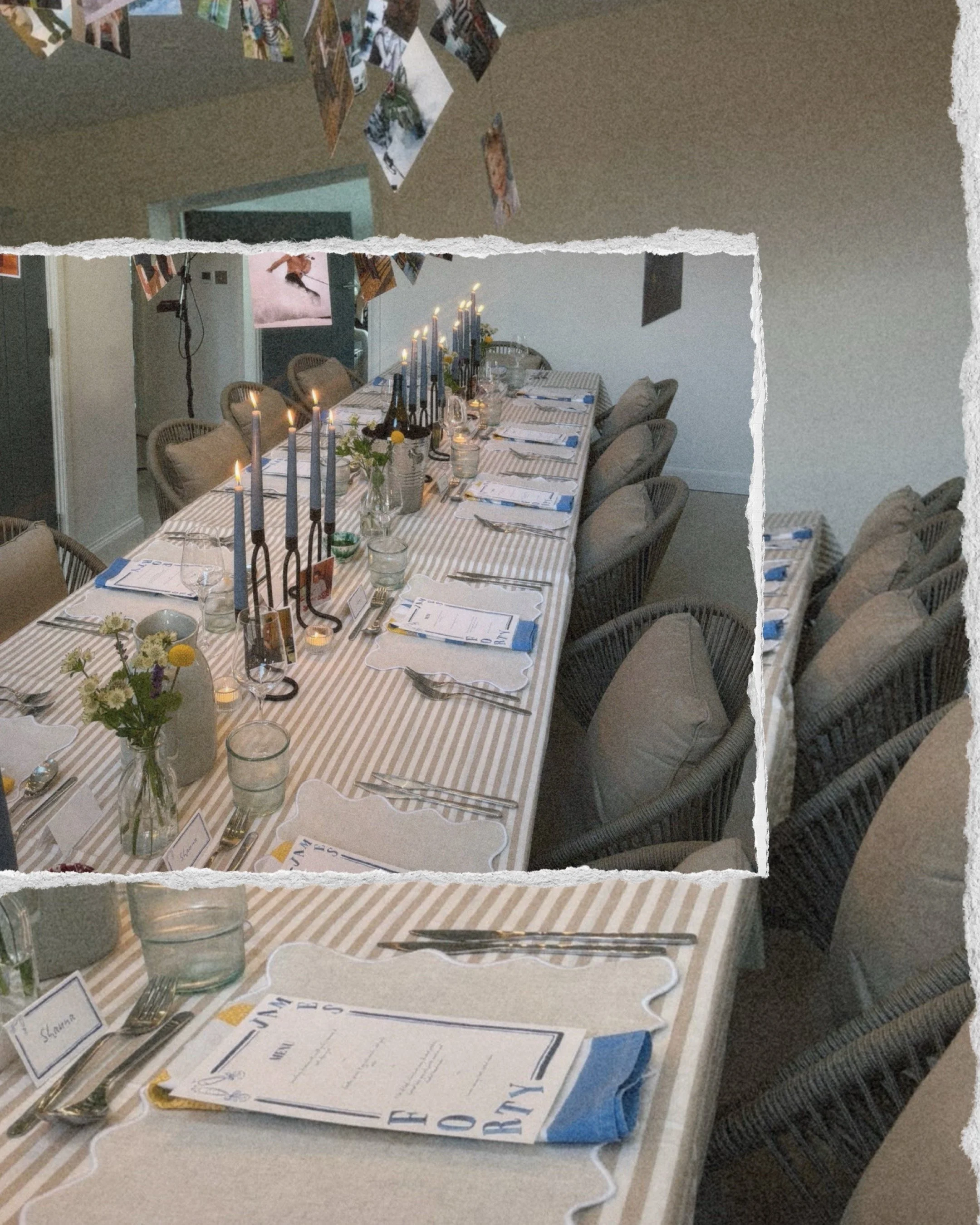 A long dining table set for a formal dinner with candles, wine bottles, flower arrangements, and place settings, in a room with hanging photos on the ceiling.