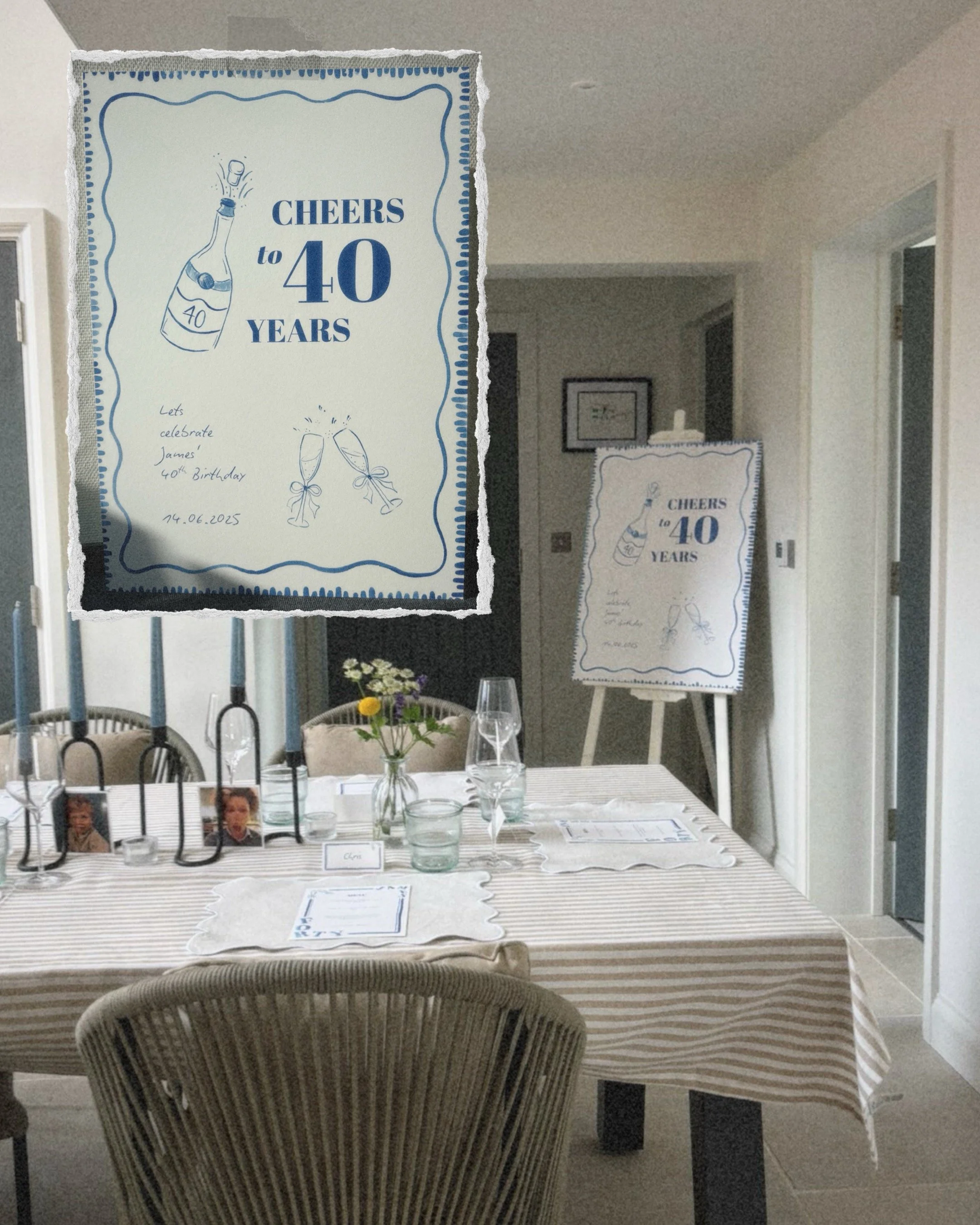 A decorated table set for a celebration, with a large sign on an easel reading 'Cheers to 40 Years' and a smaller sign with similar text. The table has flowers, candles, glasses, and placemats, indicating a festive gathering.