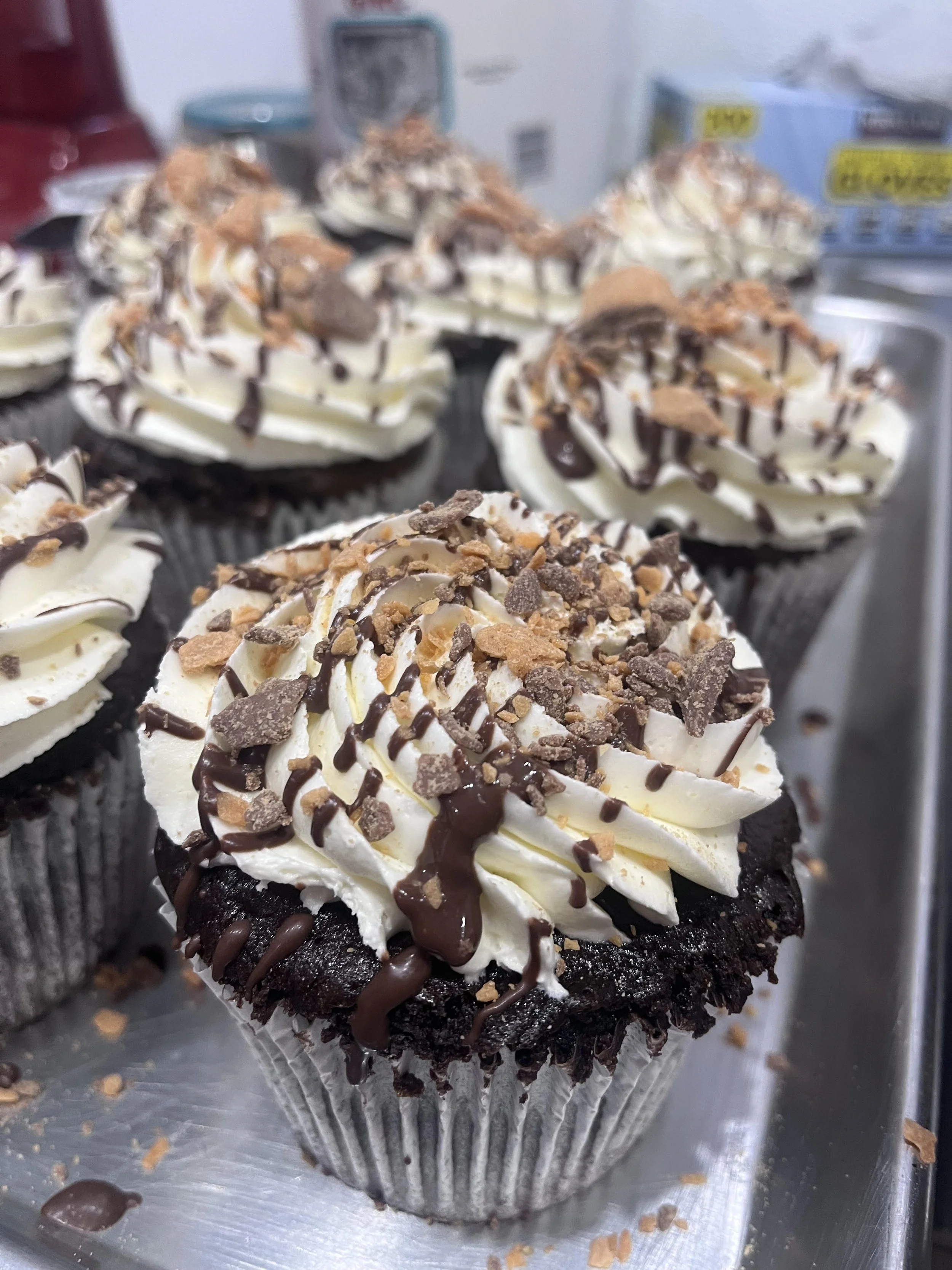 Chocolate cupcake with white frosting, chocolate drizzle, and chocolate and nut topping. Gluten free.