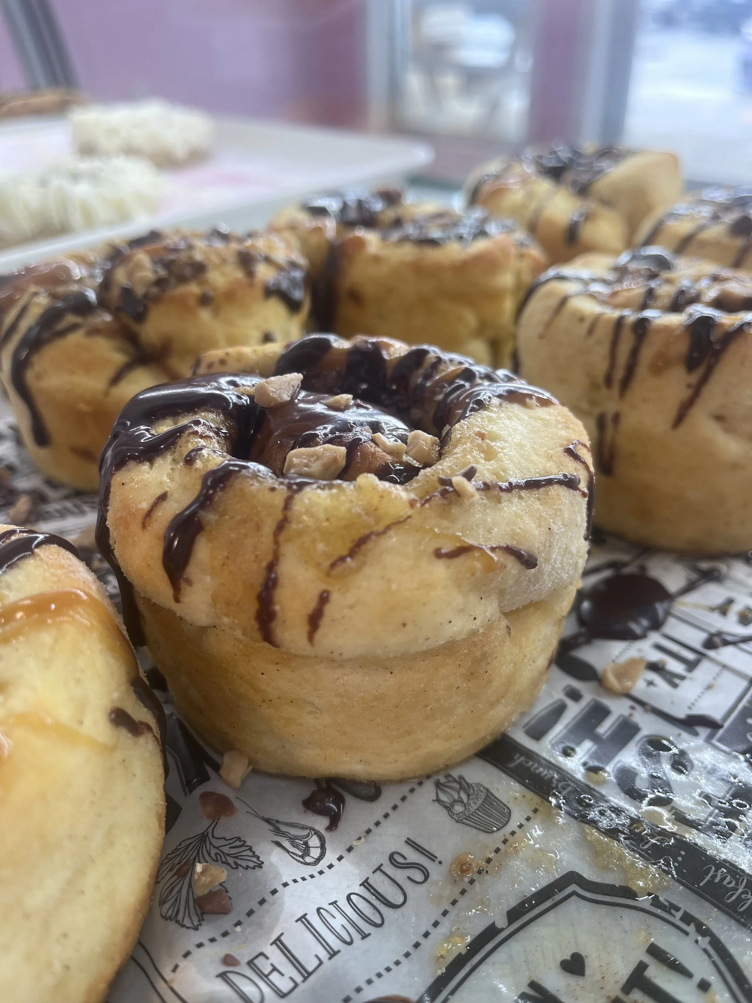 Chocolate drizzled mini cinnamon rolls topped with chopped nuts on a tray. Gluten free.
