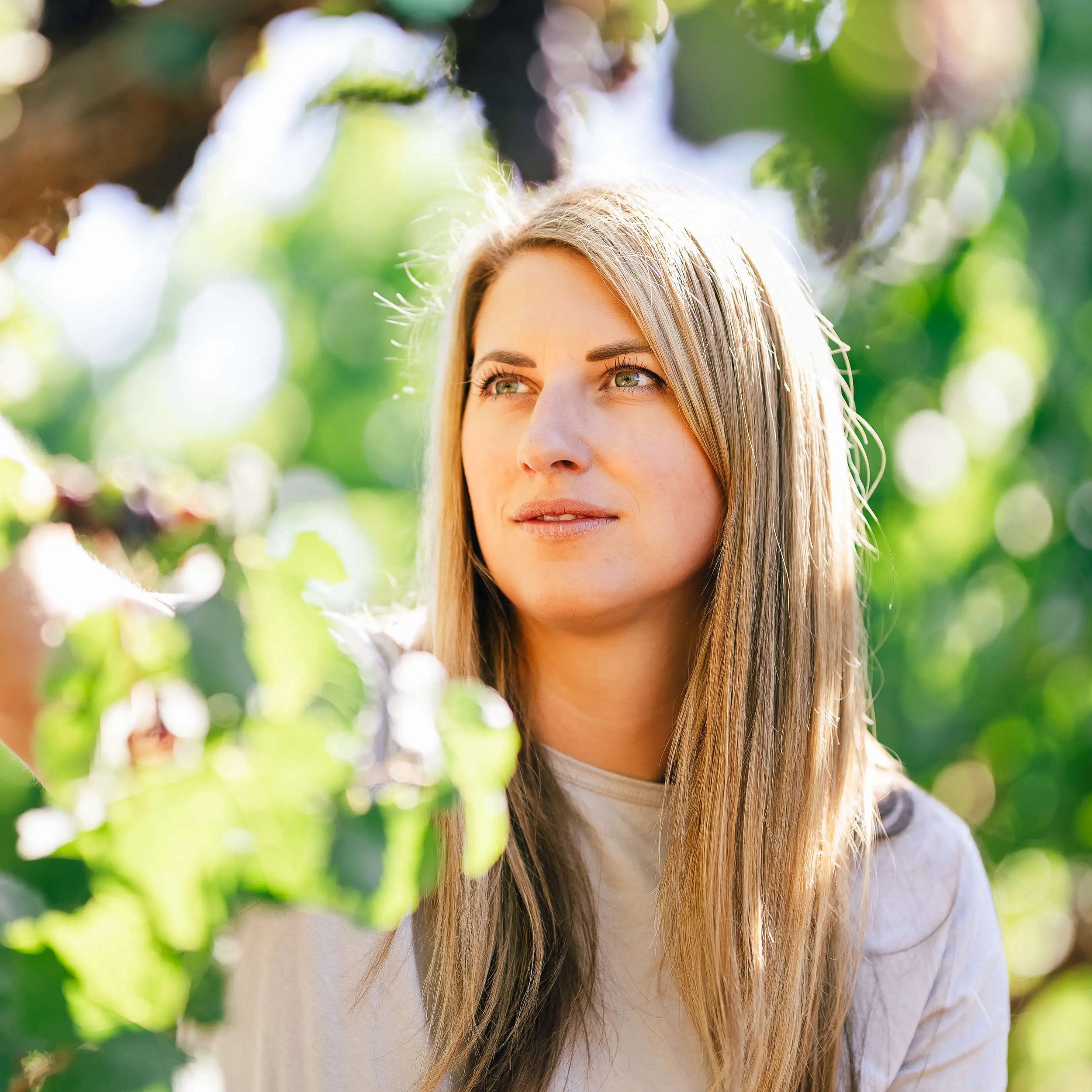 portrait of winemaker Erica Stancliff standing among sunlit grapevines