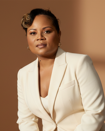 Portrait of a woman with short hair wearing a white blazer, looking confident against a beige background.