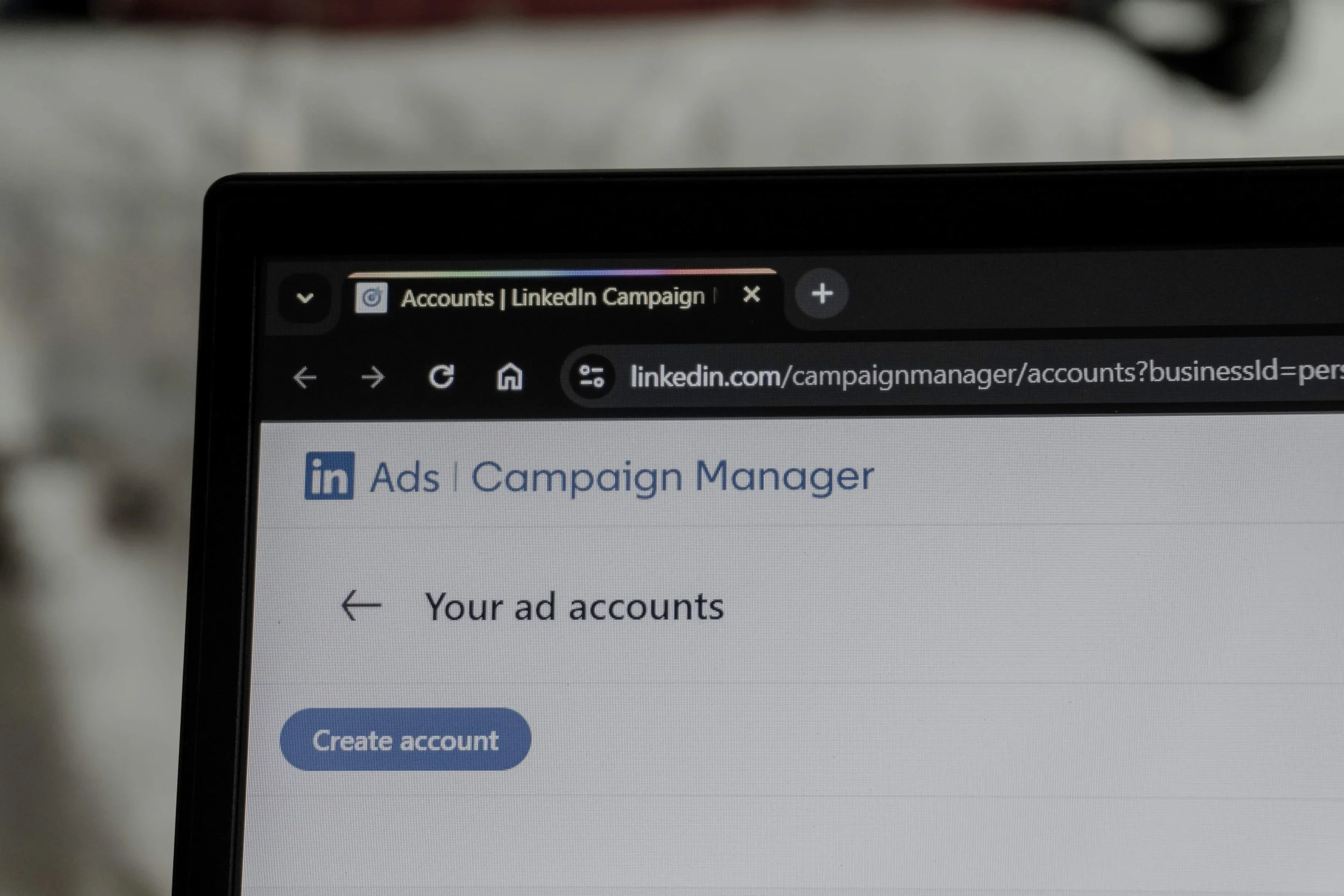 A laptop screen displaying a web browser open to the LinkedIn Ads Campaign Manager dashboard, showing the menu structure and the 'Your ad accounts' page, for managing digital advertising.