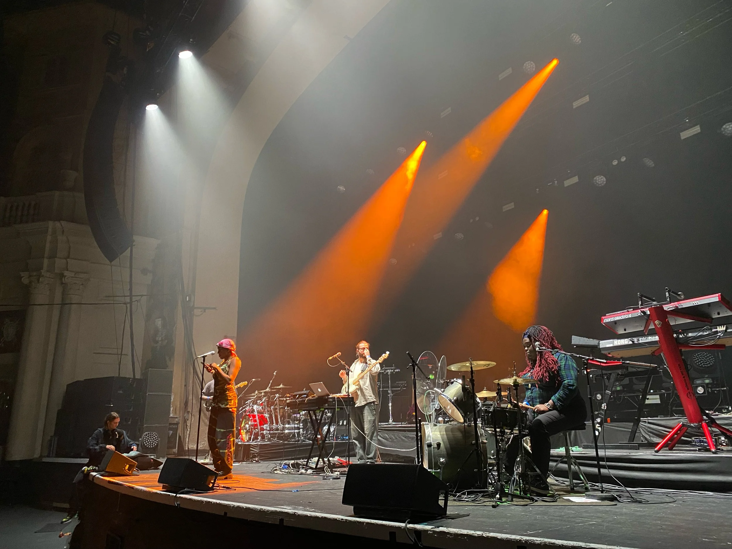 Musicians performing on stage with orange stage lights illuminating the scene.