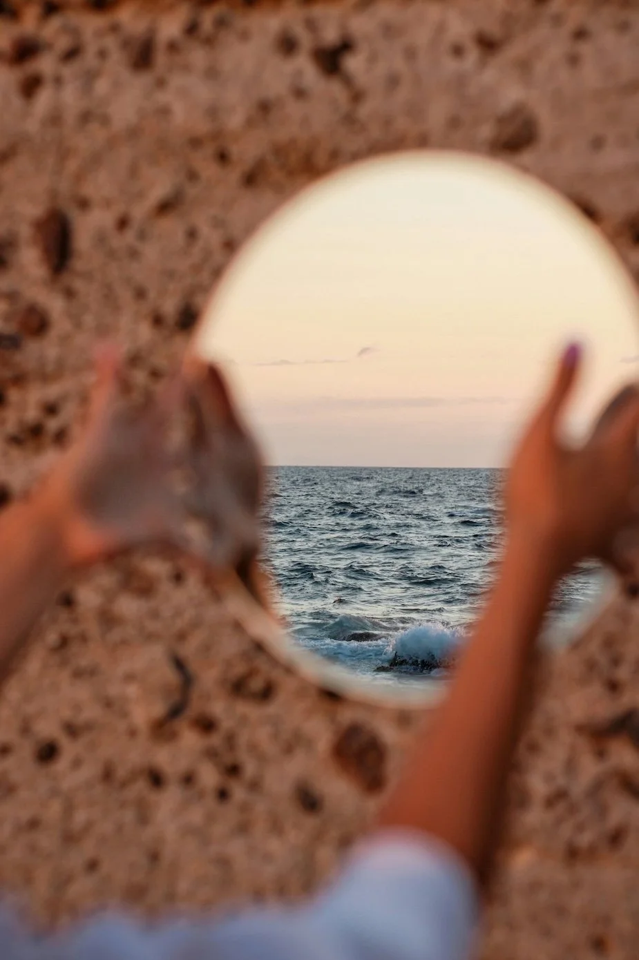 Person holding a seashell up to the ocean view at sunset, with cloudy sky and gentle waves. naturopath Eloise smith from clean slate naturopathy reflects on her journey