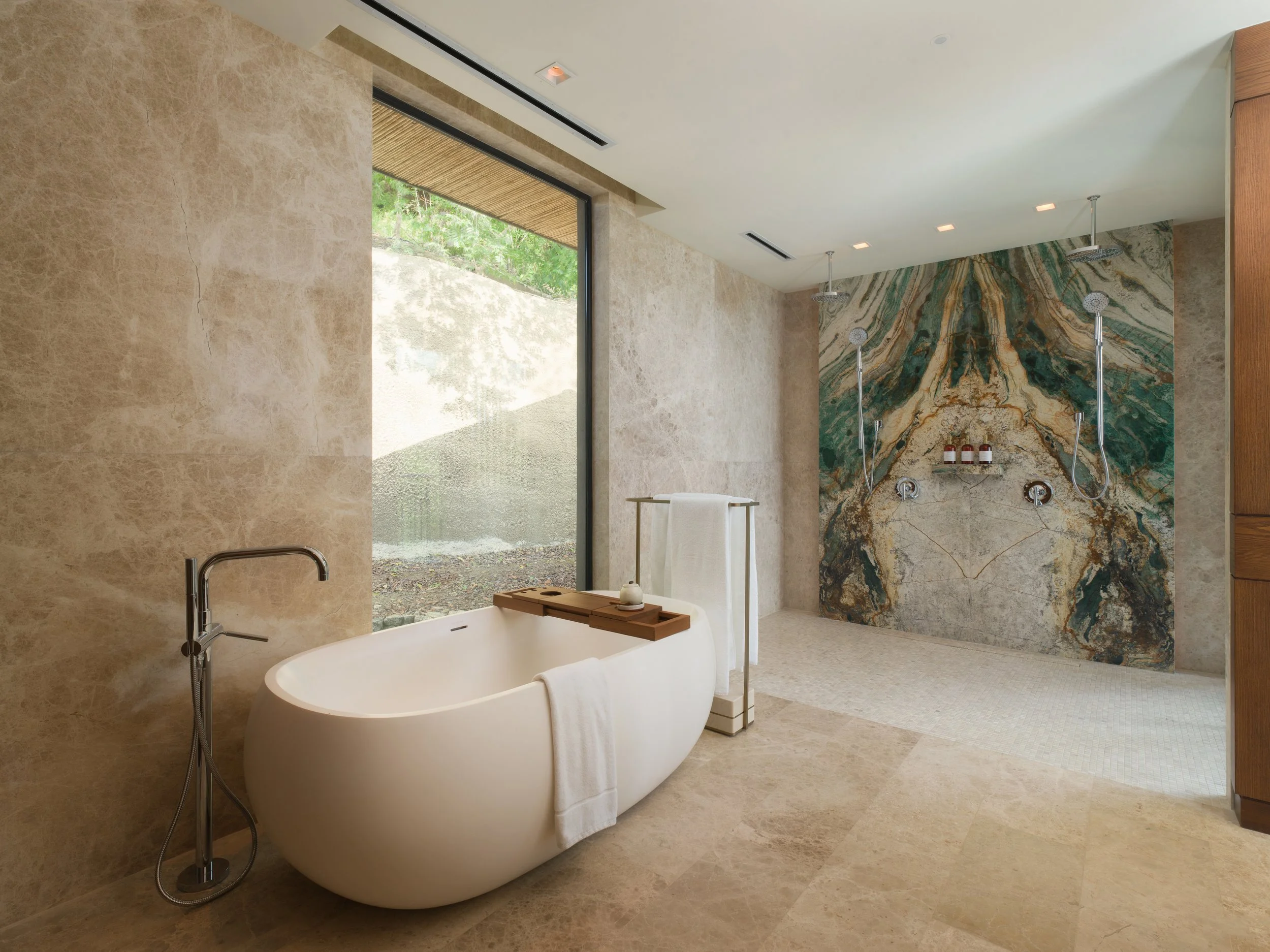 Modern bathroom with free-standing bathtub, large window, and a walk-in shower with a marble accent wall.