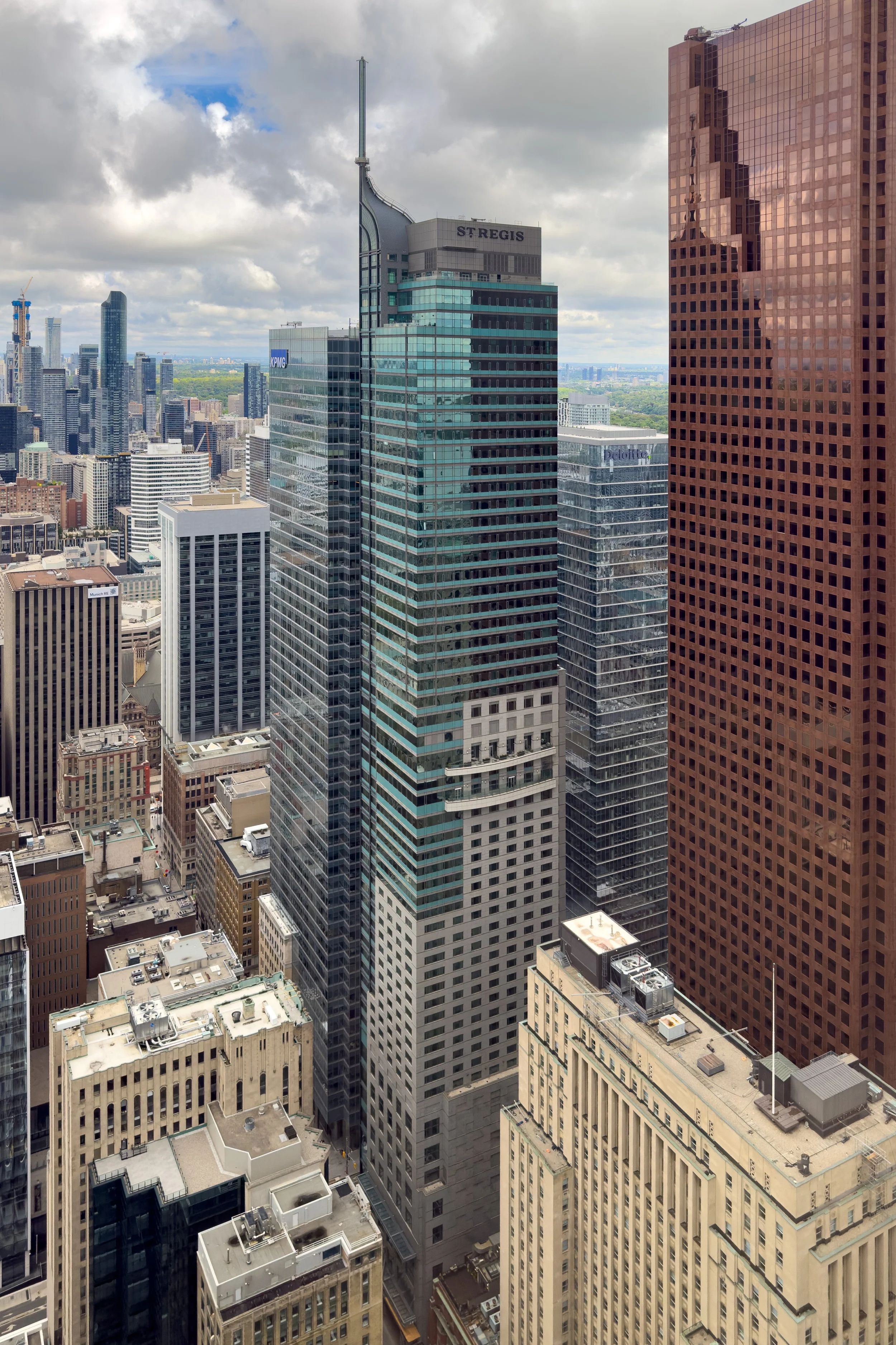 A cityscape of tall modern skyscrapers, including the St. Regis hotel, under a partly cloudy sky.