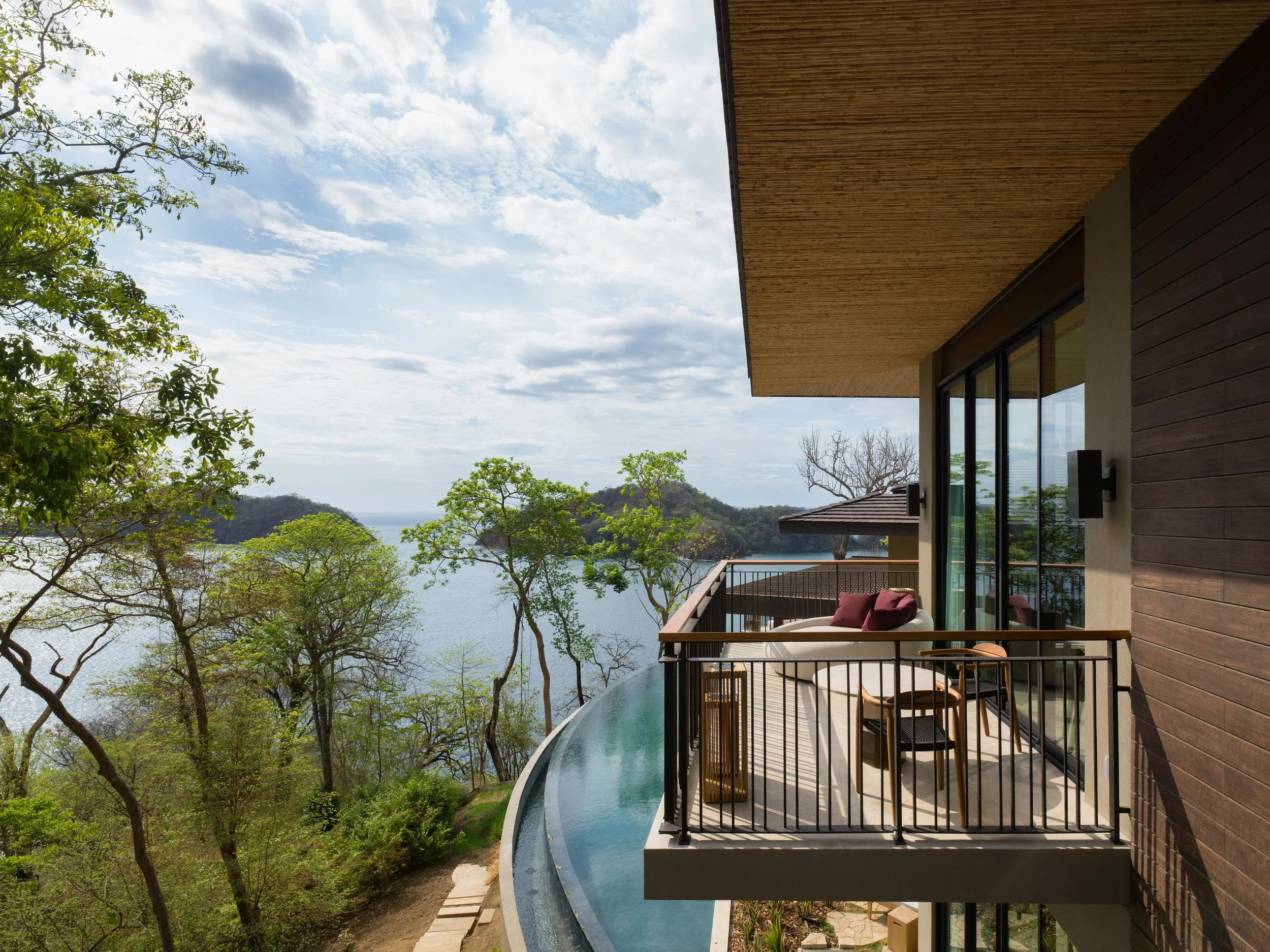 Balcony overlooking a lake surrounded by trees at a modern house.