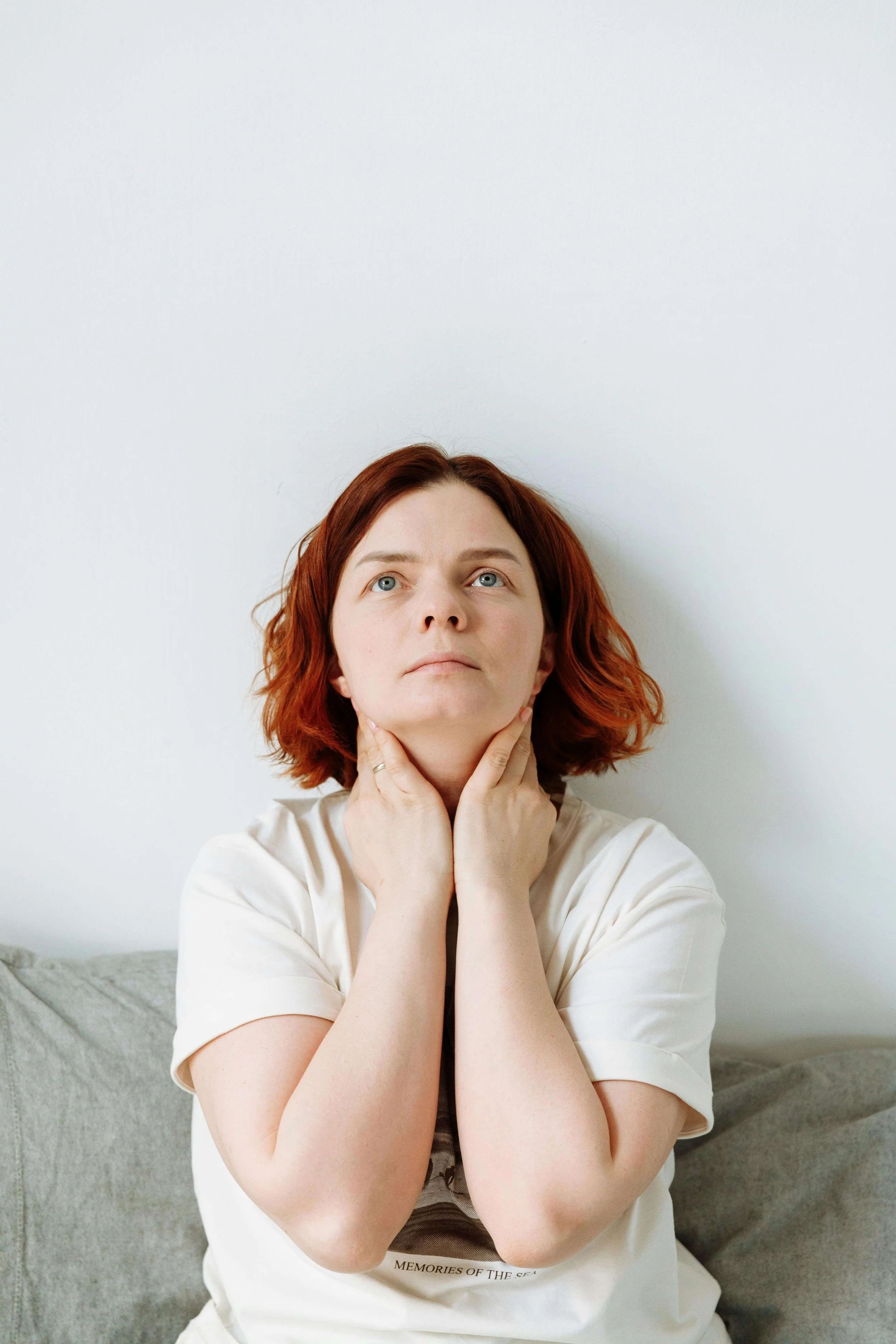 A woman with short red hair rubbing her neck & looking up in distress. Representing how stressful times & the holiday season can make your OCD worse. Discover how therapy for OCD in Boston, MA can help you reclaim this season!