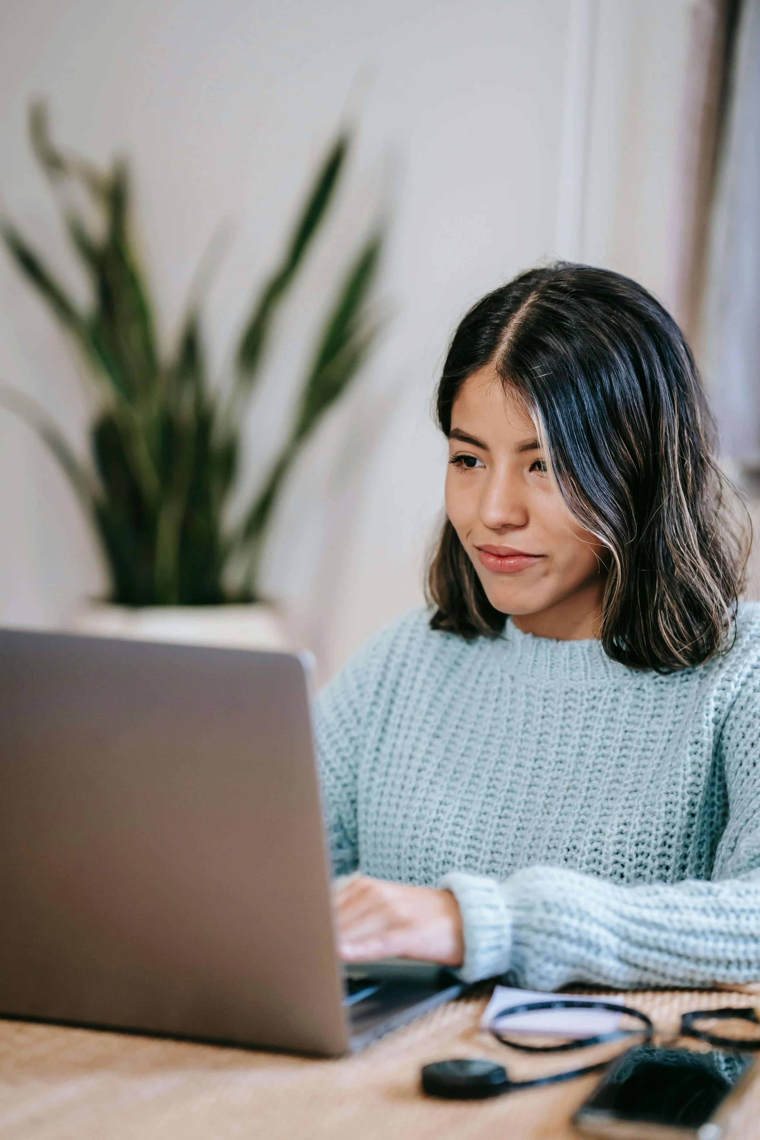 A biracial woman smiling as she looks at her laptop. I offer online OCD therapy in Boston, MA to help individuals manage their OCD and anxiety. Learn more here!