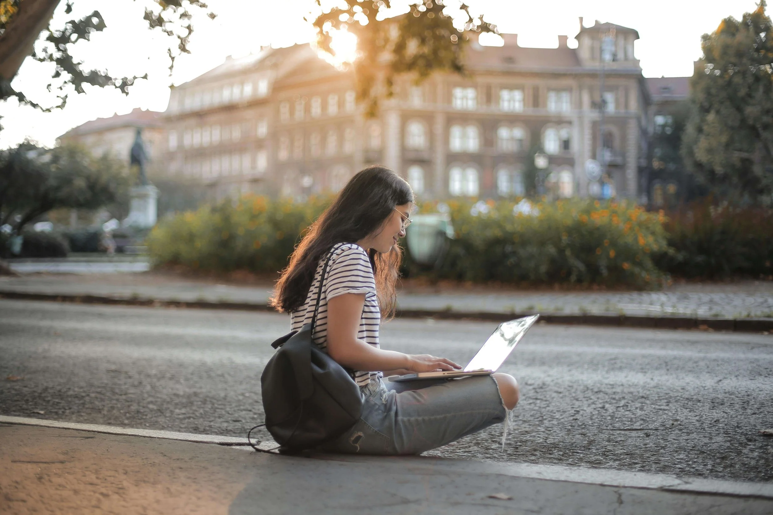 A young adult woman sitting near a college building & typing on a laptop. If OCD is disrupting your life, seeking OCD therapy in Boston, MA might be the next step toward recovery.