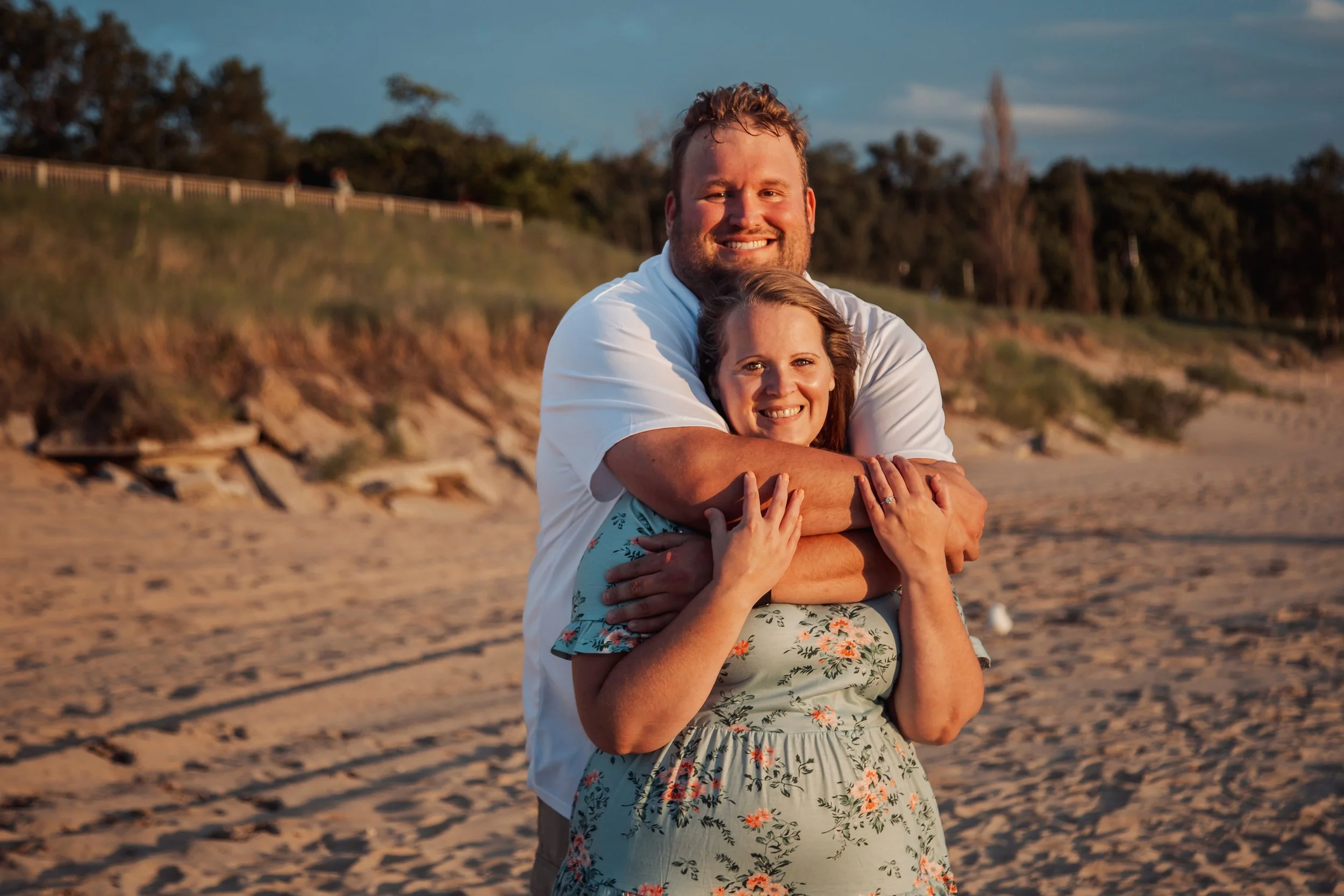 A happy couple embracing on a sandy beach during sunset.