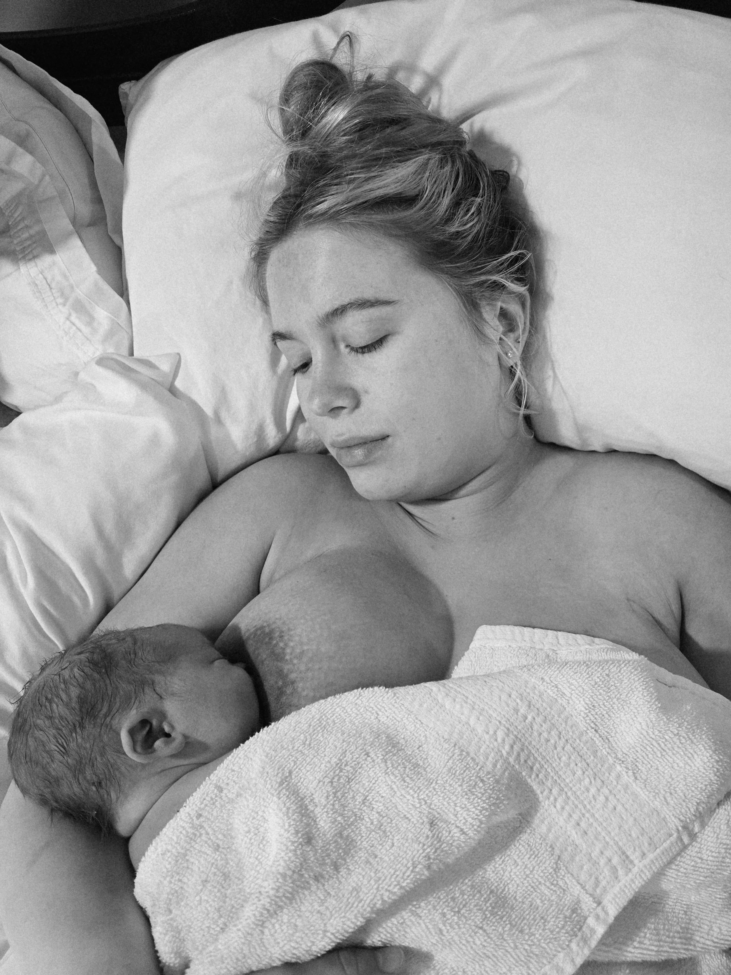 Black and White image of mom breastfeeding brand new baby right after birth