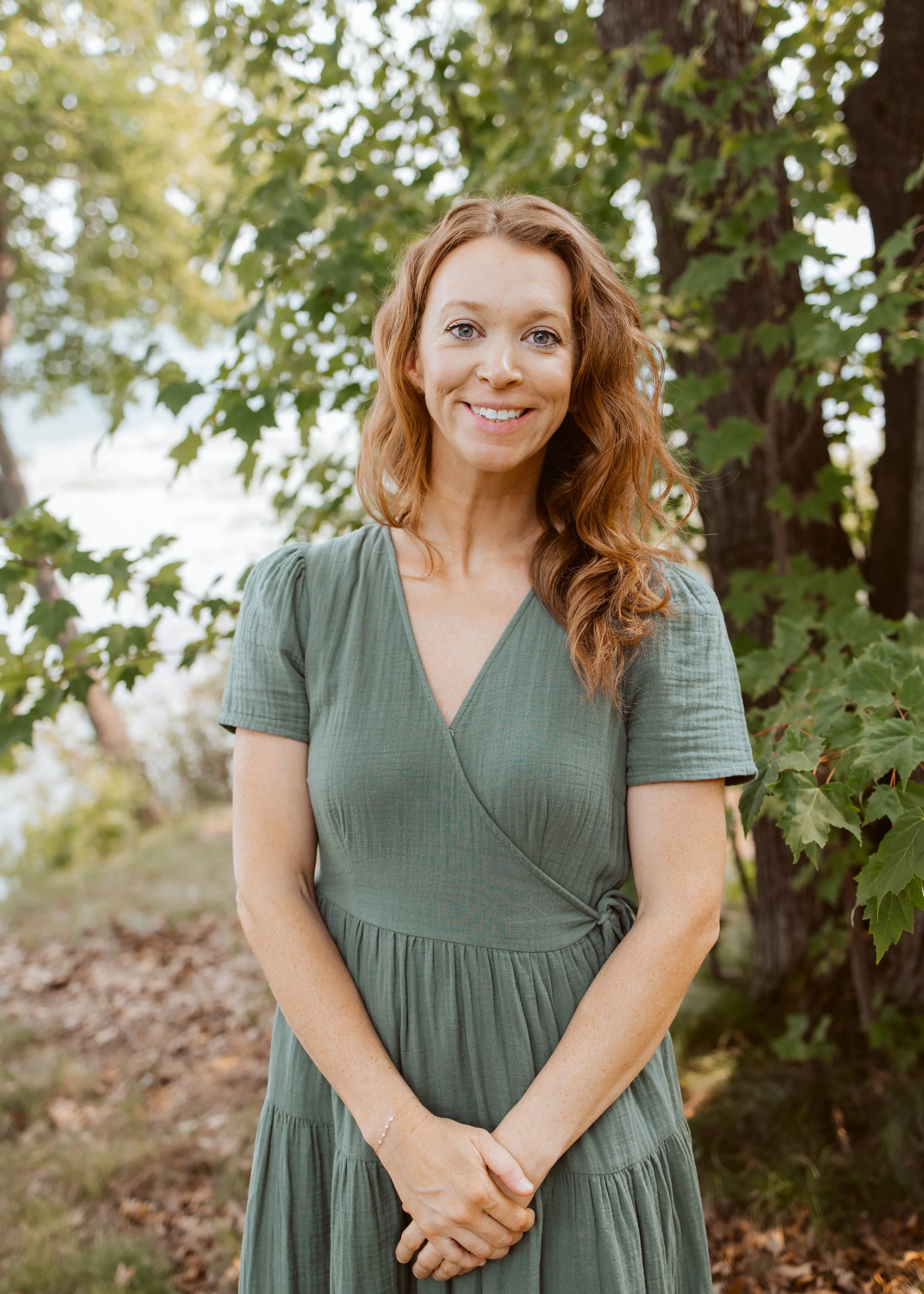 Woman in green dress outside by trees and lakefor portrait photo