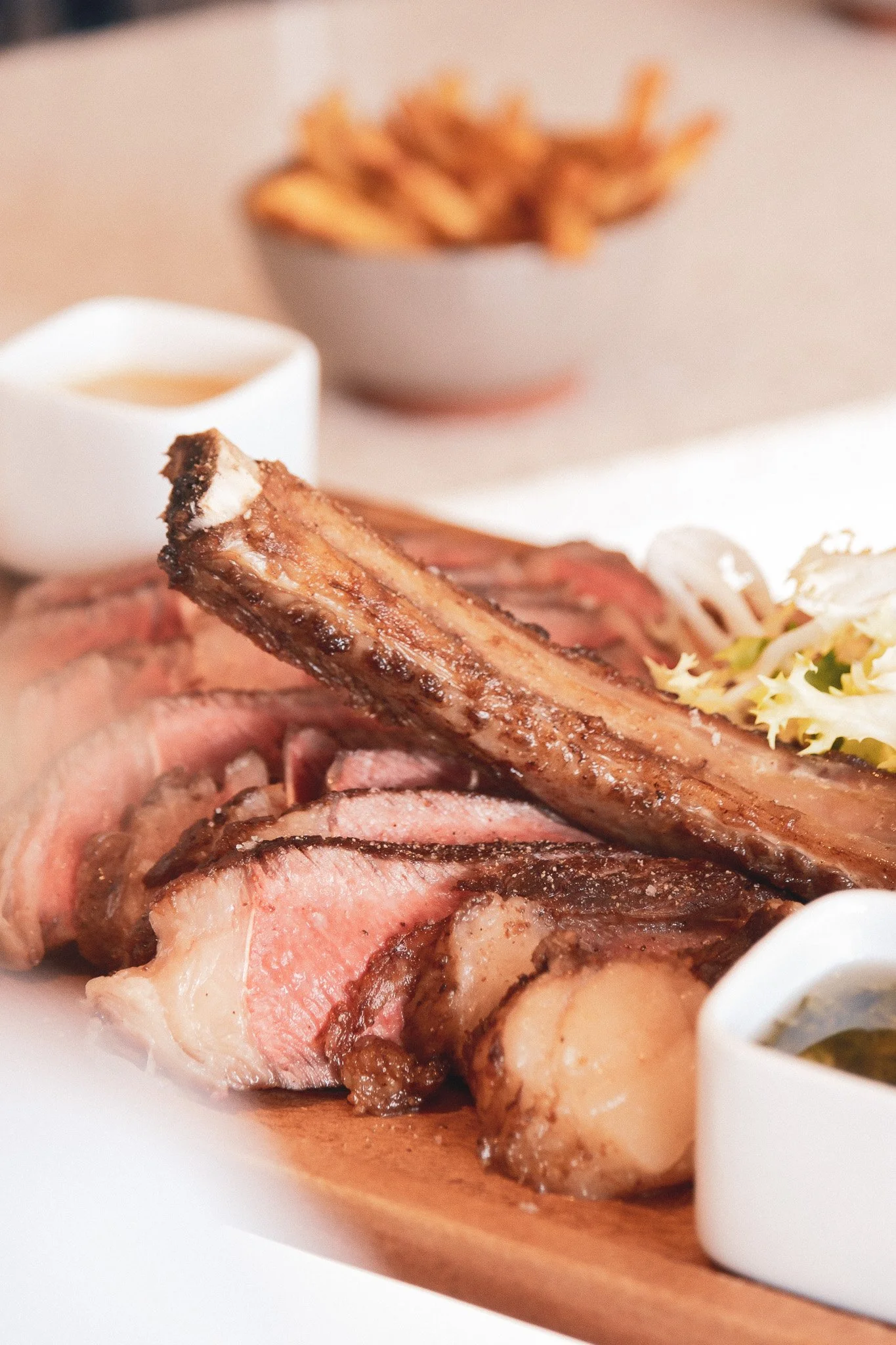 Une assiette de viande rôtie avec des garnitures et une sauce, accompagnée de frites.
