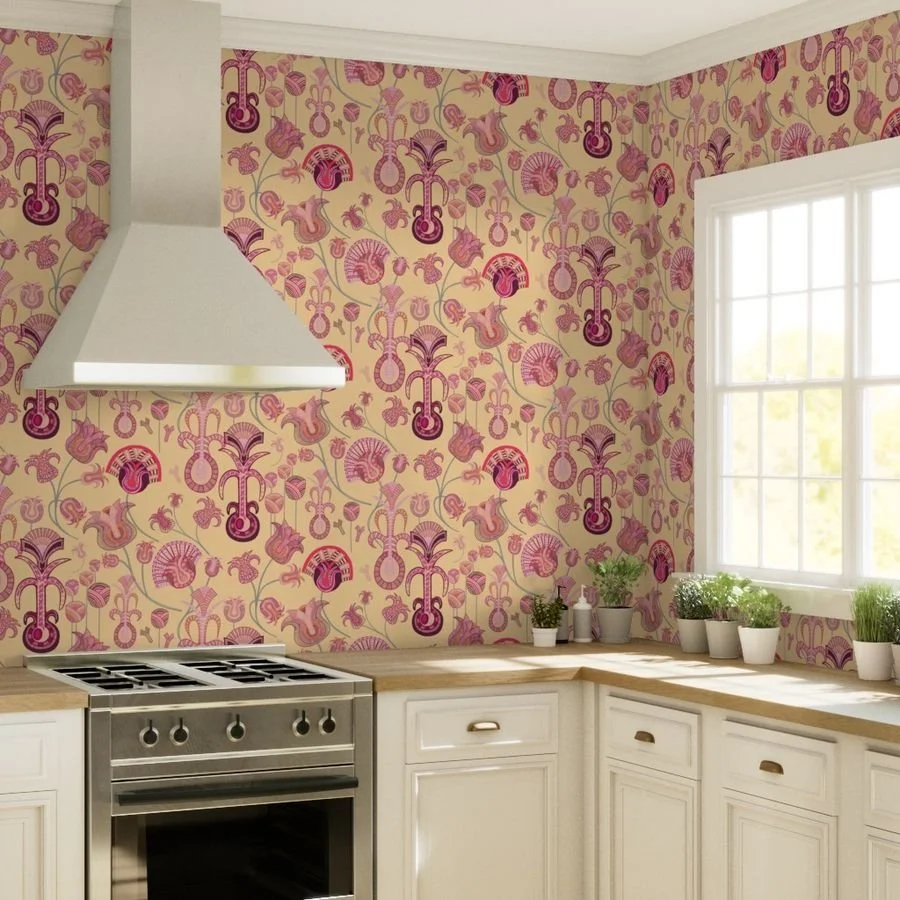 Layered tulip-like forms with intricate detail play across a warm creamy yellow wallpaper in a brightly lit modern kitchen with potted plants under the window