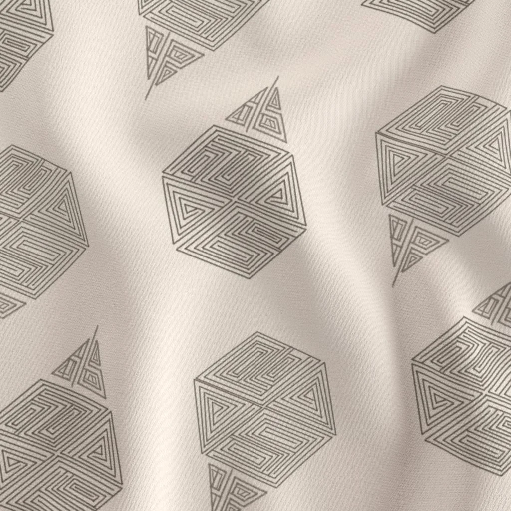 A close-up of hand-drawn hexagon fabric in cream and grey-taupe, showing individual hexagon motifs against the fabric's natural drape. Maze-like nested line work fills each hexagon with visible space between motifs.