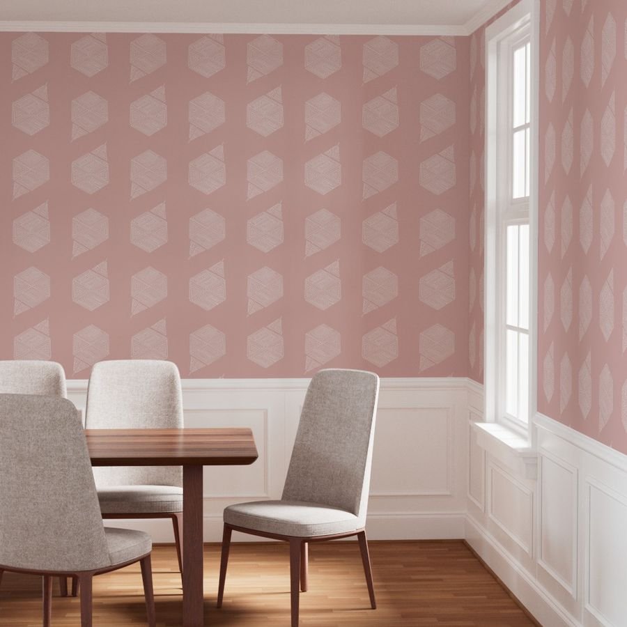 Blush pink geometric hexagon wallpaper shown lining a dining room above white wainscoting. Hand-drawn line work in a larger-scale repeat gives the pattern an open, airy presence in a light-filled room.