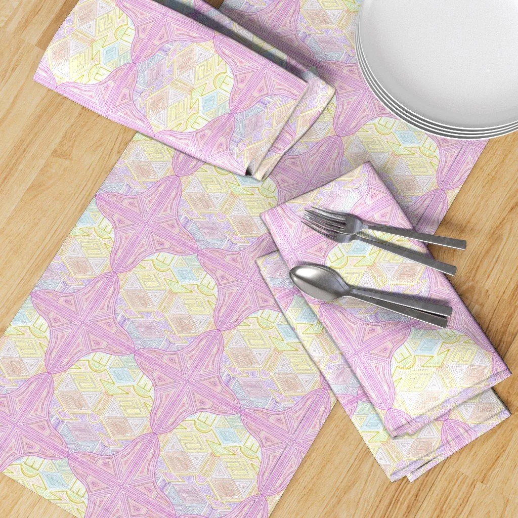 Jewel-colored repeated pattern on a table runner and napkins with silverware and a white plate atop a light oak wood table