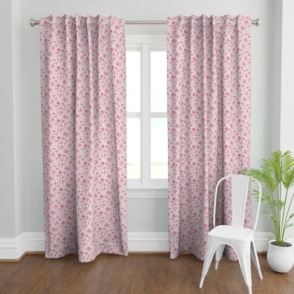 Whimsical tulips meander and sprout with detailed vibrancy against a light pink ground on curtains in a bright room with a pale gray wall behind a white metal chair and green fern in a white pot on a walnut wood floor