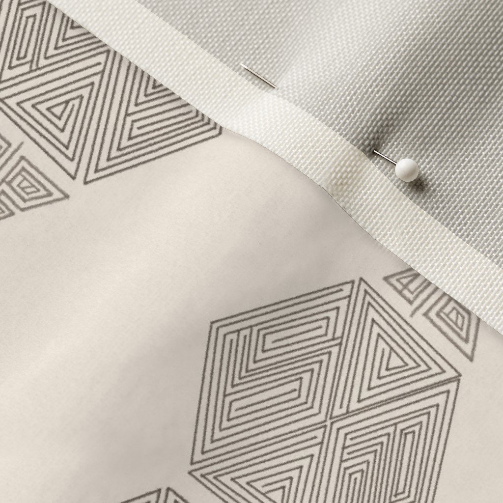 A close-up of hand-drawn hexagon fabric in cream and grey-taupe with a dressmaker's pin