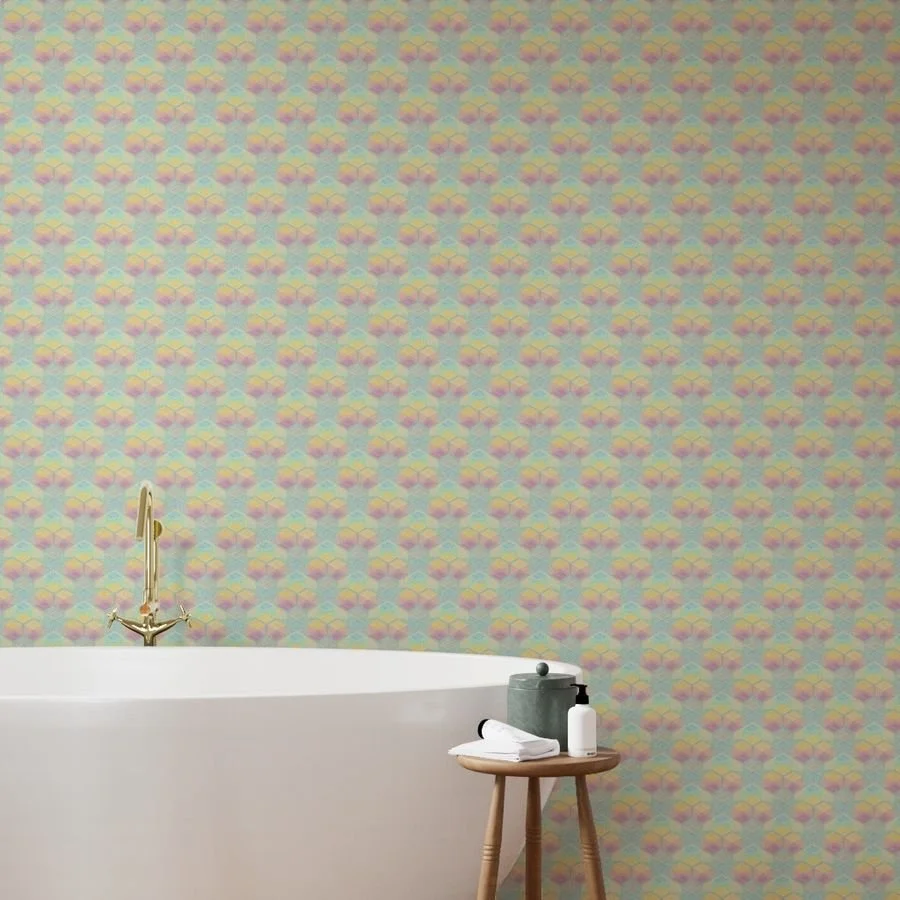 Soft pastel geometric wallpaper in teal, pink, and yellow lines a bathroom wall behind a white freestanding tub with brass fixtures.