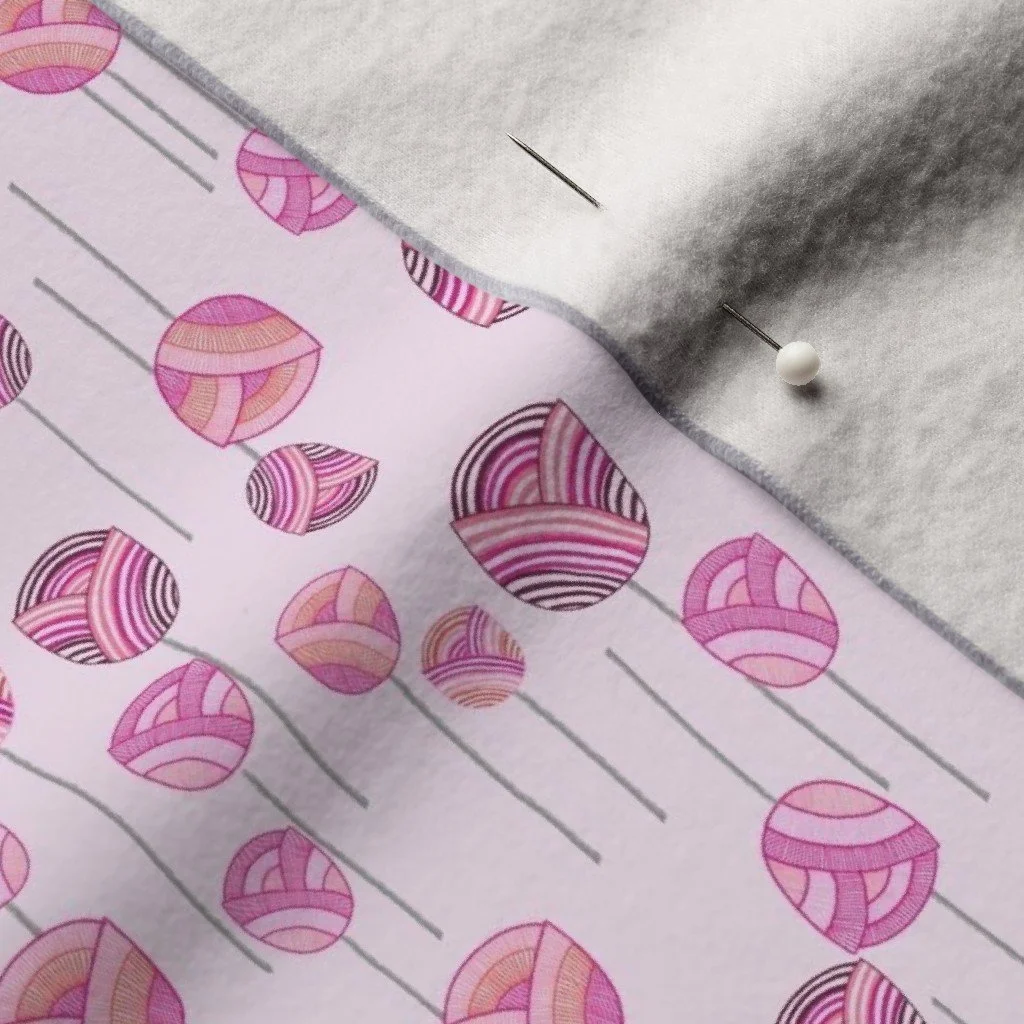 A dancing floral ditsy pattern with abstract tulips and stems on a light pink background on a warm felt cloth with a pearl dressmaker's pin