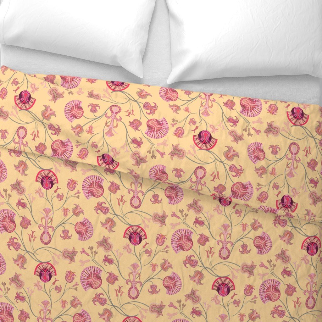 A yellow duvet with pink branching tulip-inspired bouquets sit atop pristine white sheets under white pillows on a bed