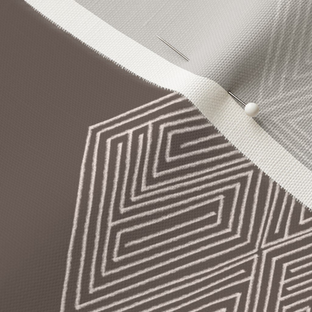 A brown and taupe hand-drawn hexagon on fabric with a dressmaker’s pin.