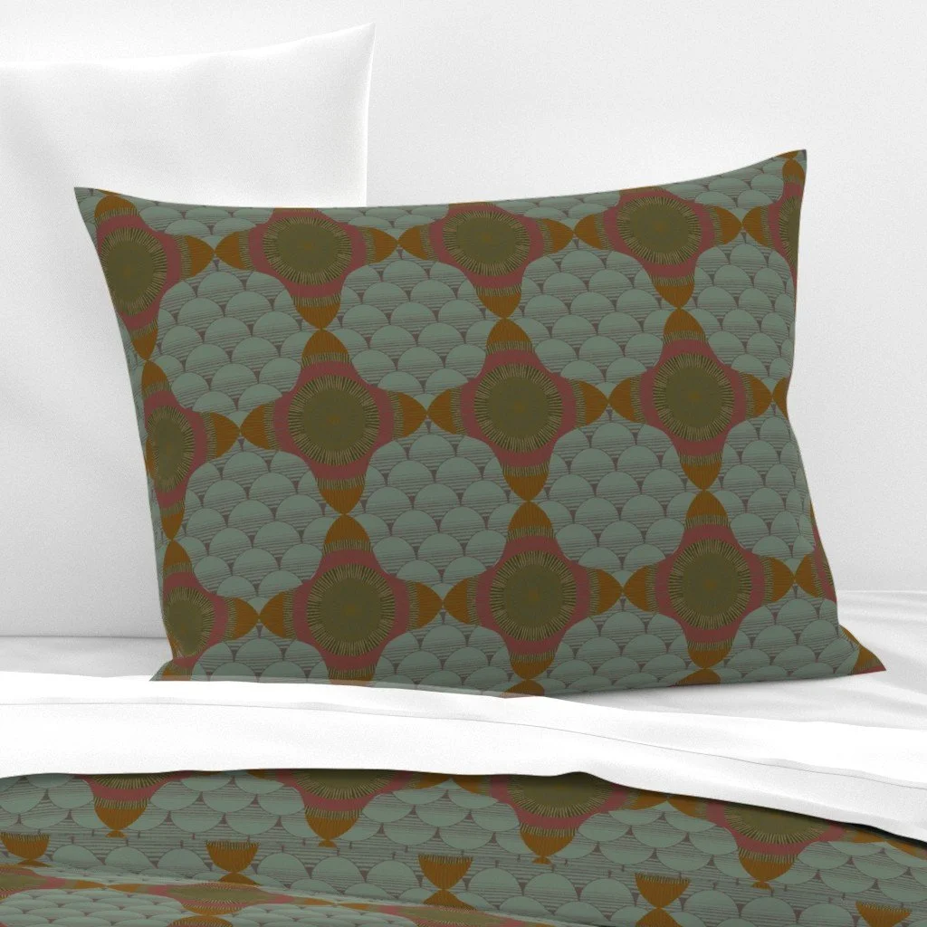 Gray green with fish scale and center star fabric design on a pillow sham, lying on top of crisp white sheets