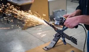 Person using a grinding tool on a metal object, producing sparks in a workshop.
