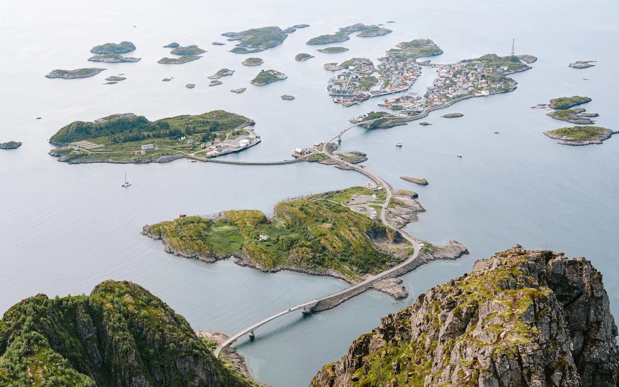 Aerial view of a coastal region with islands, a bridge, and a small town surrounded by water and rocky landscapes.