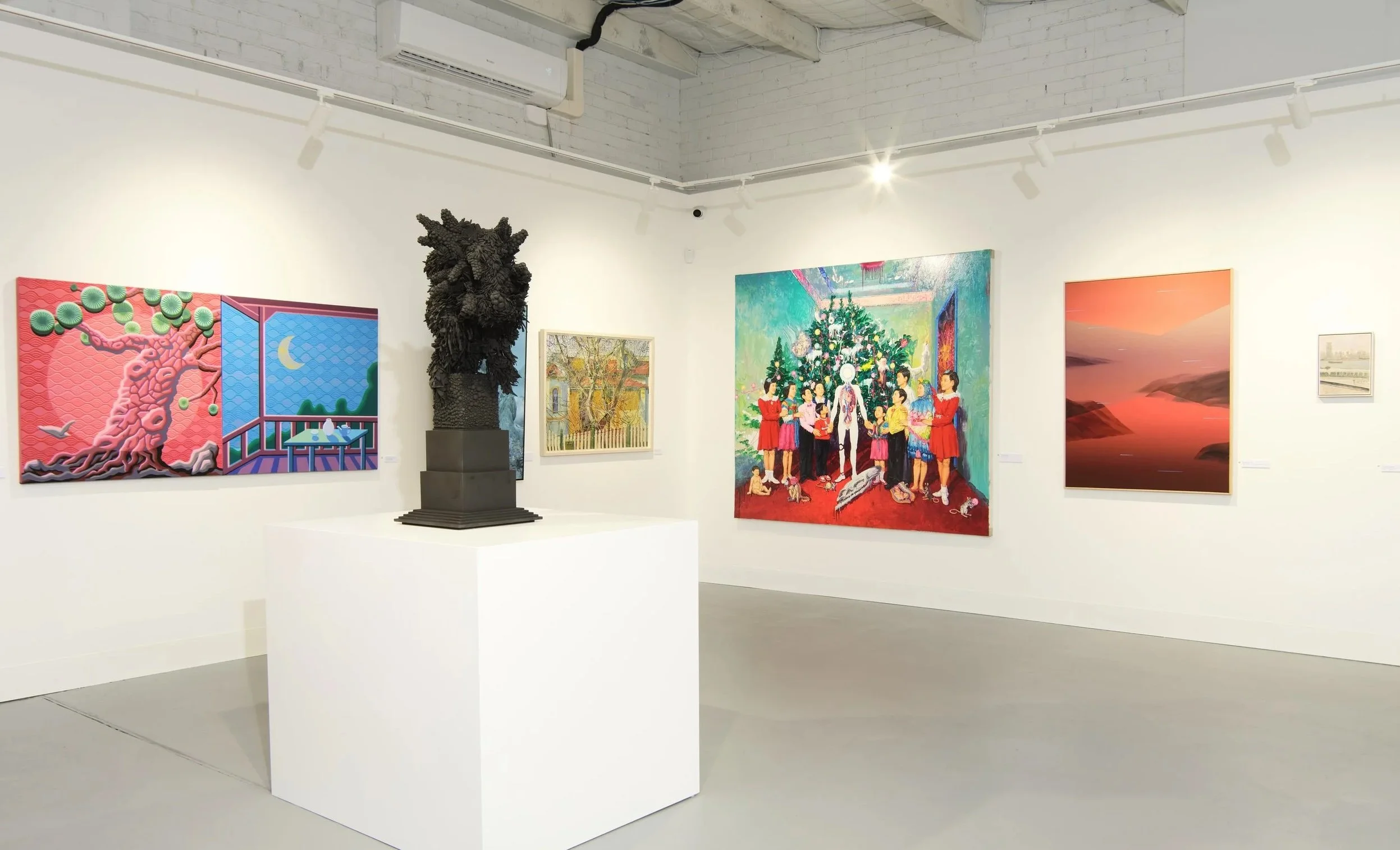 Art gallery with colorful paintings on white walls and a black sculpture on a pedestal in the center.