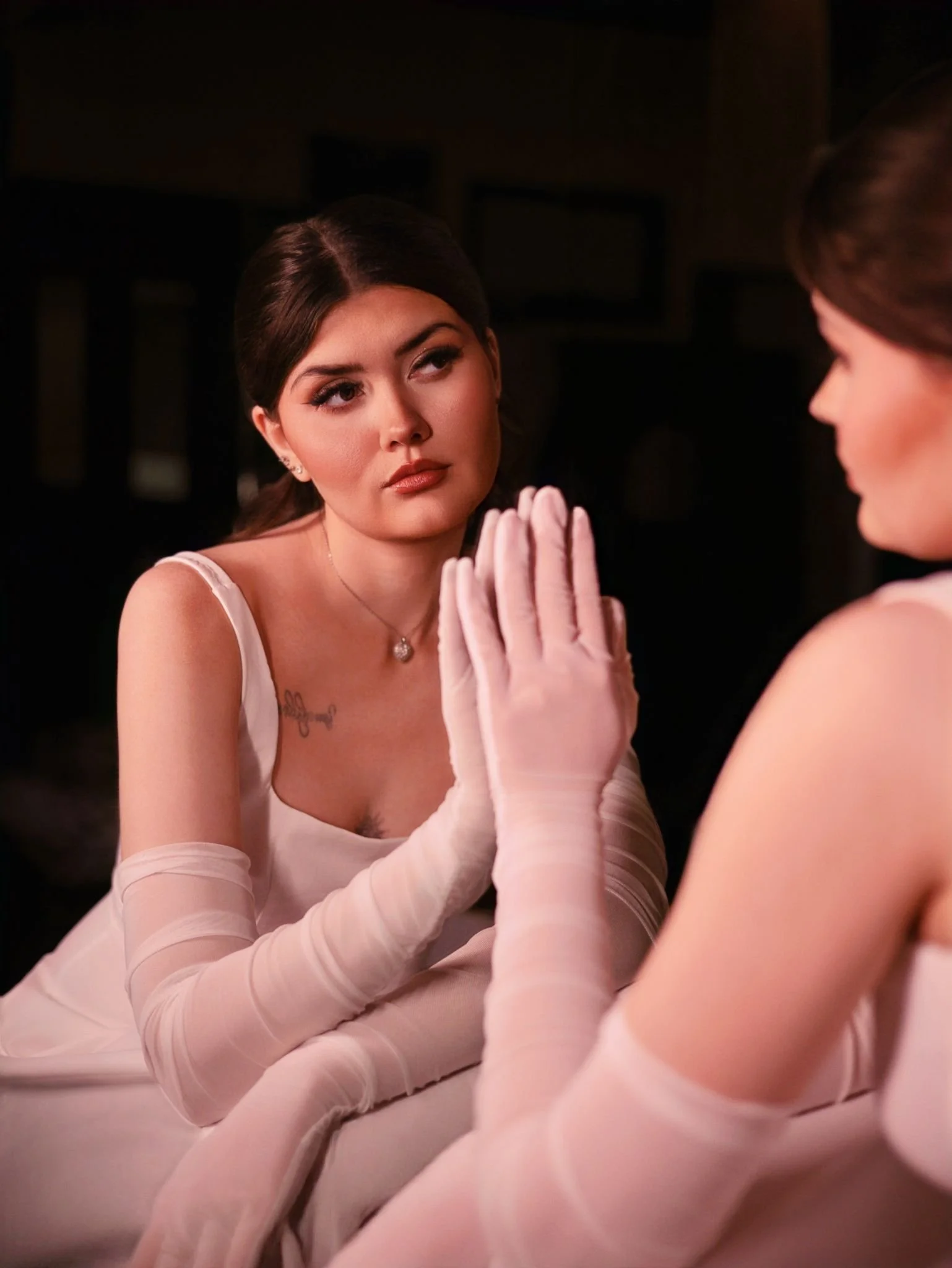 Close-up of bride's clasped hands in sheer gloves, soft glam bridal makeup styling.