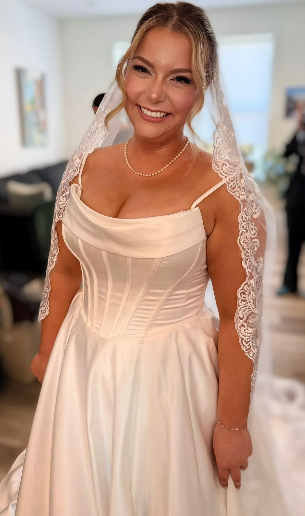 Smiling bride in a corset-style wedding gown and veil.