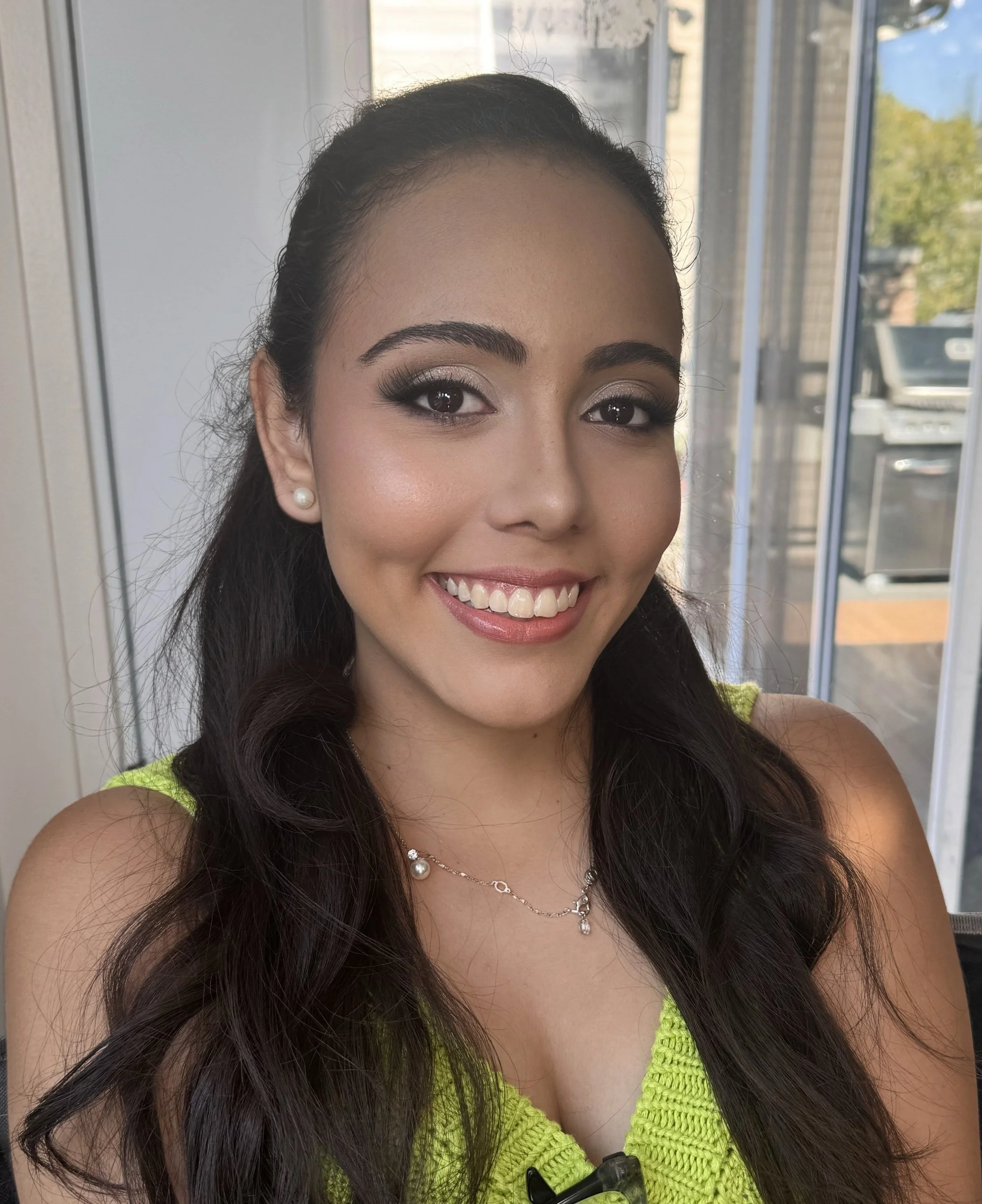 Soft glam bridal makeup with defined brows, styled in a half-up look with loose waves.