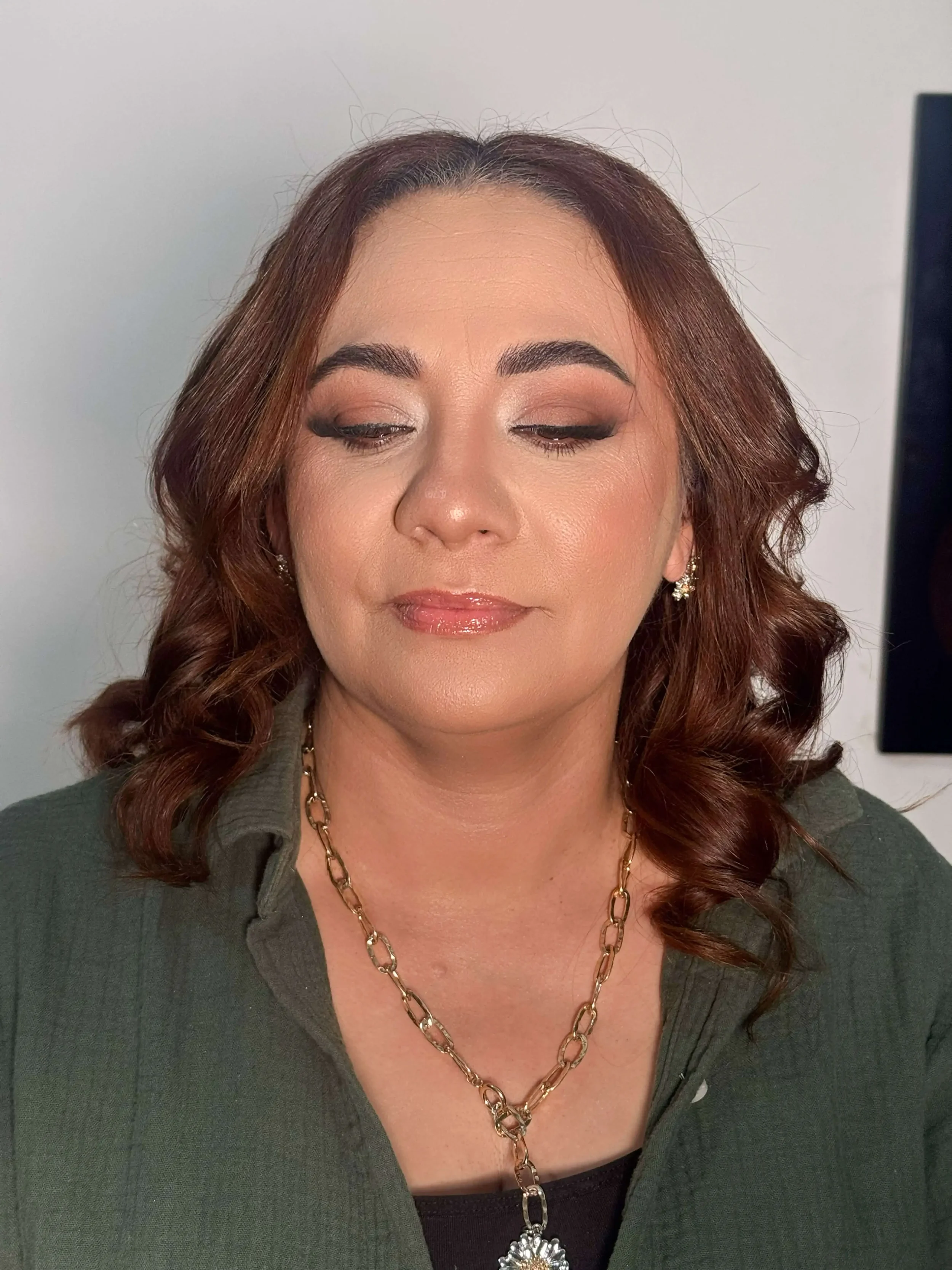 Natural glam makeup with warm brown eyeshadow, soft eyeliner, subtle lashes, glowing skin, and glossy nude lips.