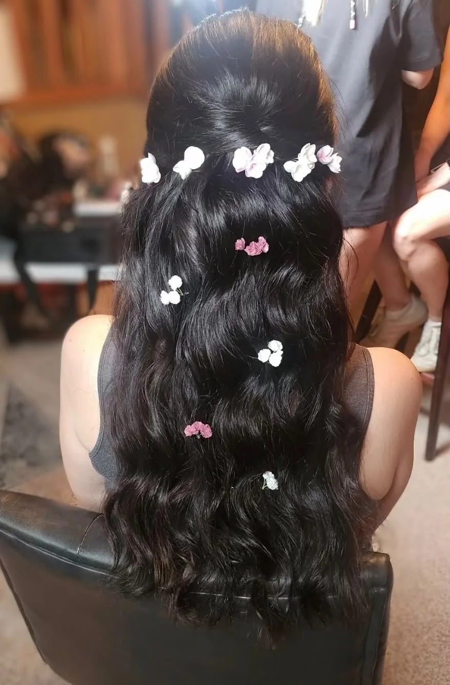 Half-up bridal hairstyle accented with small white and pink flower clips.