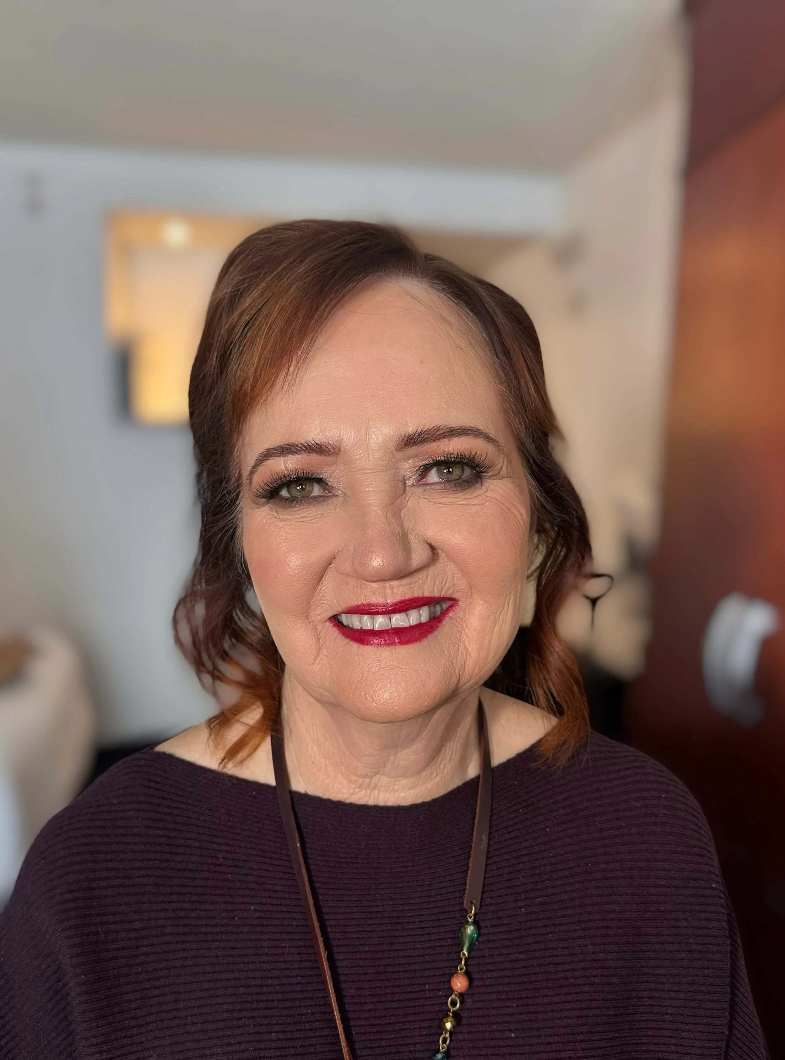 Natural glam makeup with even skin, softly defined brows, neutral eye makeup with mascara, warm blush, and bold red lipstick.