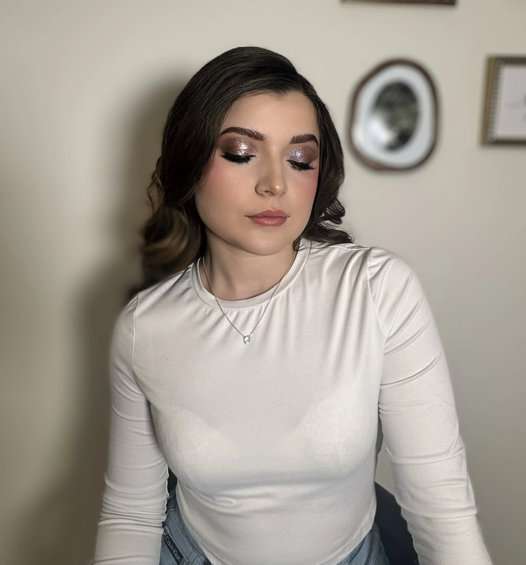Close-up of glitter eyeshadow makeup application with soft curled hair.