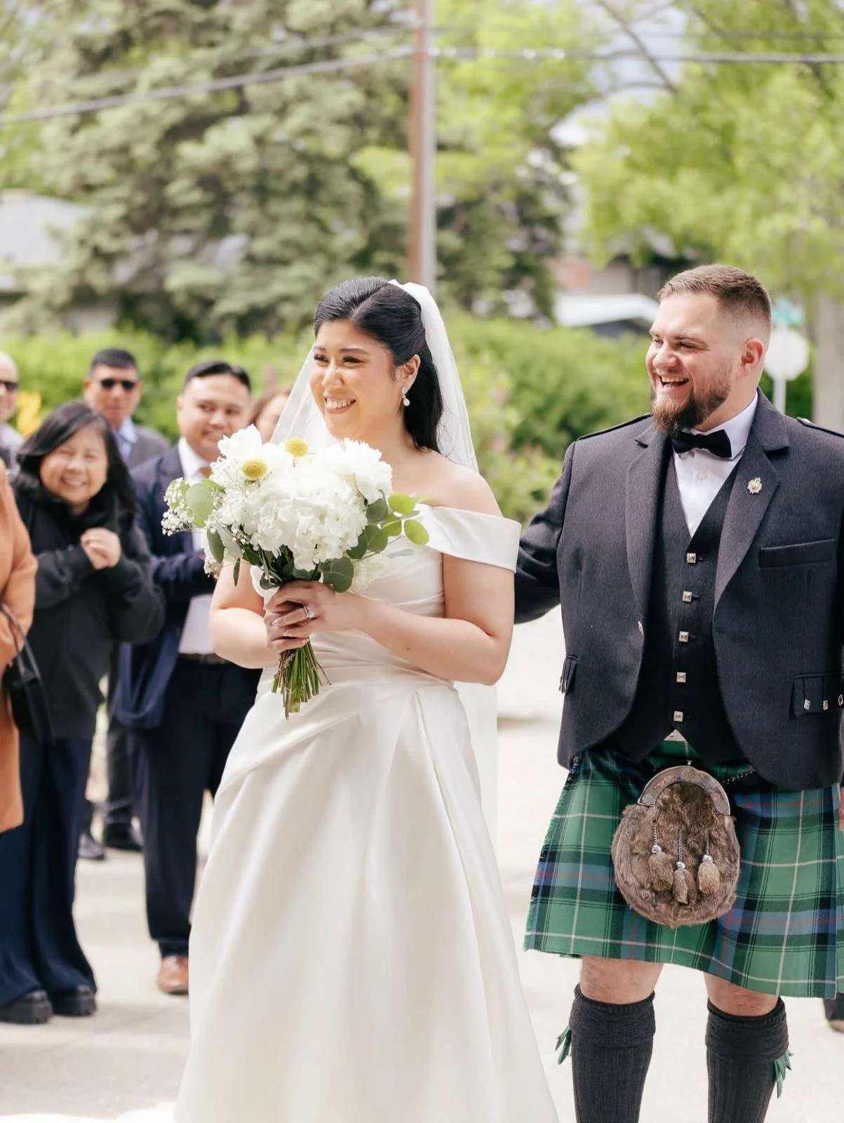 Calgary bride and groom in kilt walking outside the ceremony venue, bride holding a white bouquet