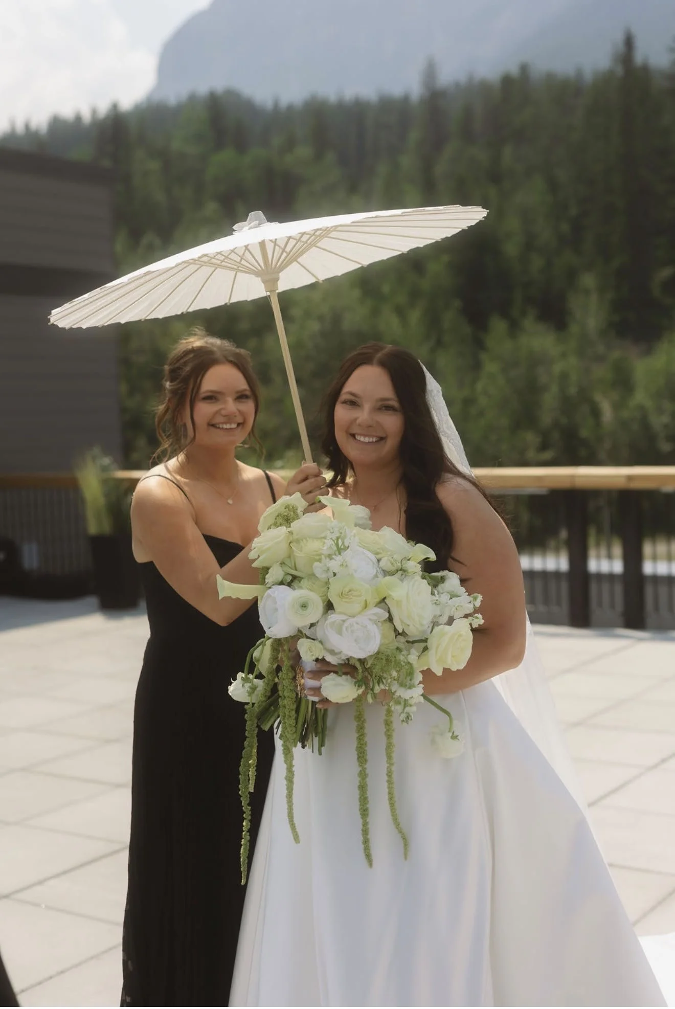Bride and bridesmaid with elegant wedding makeup and hair styling by North of Blush mobile beauty team for an outdoor Alberta wedding.