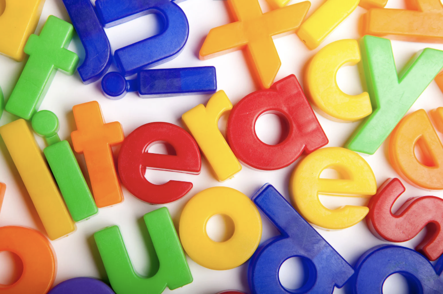 Colorful magnetic alphabet letters scattered on a white surface, including letters like E, R, Y, T, U, I, O, P, and X.